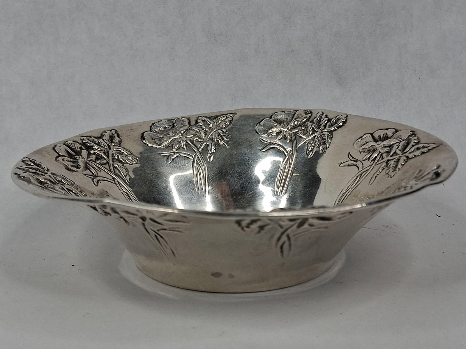 Kirk & Son for Caldwell Str. Poppy Bowl: A sterling silver repousse bowl manufactured by S. Kirk and Son and retailed by J.E. Caldwell and Co. The round bowl features a flared, lobed, and scalloped rim with high-relief repousse decoration de