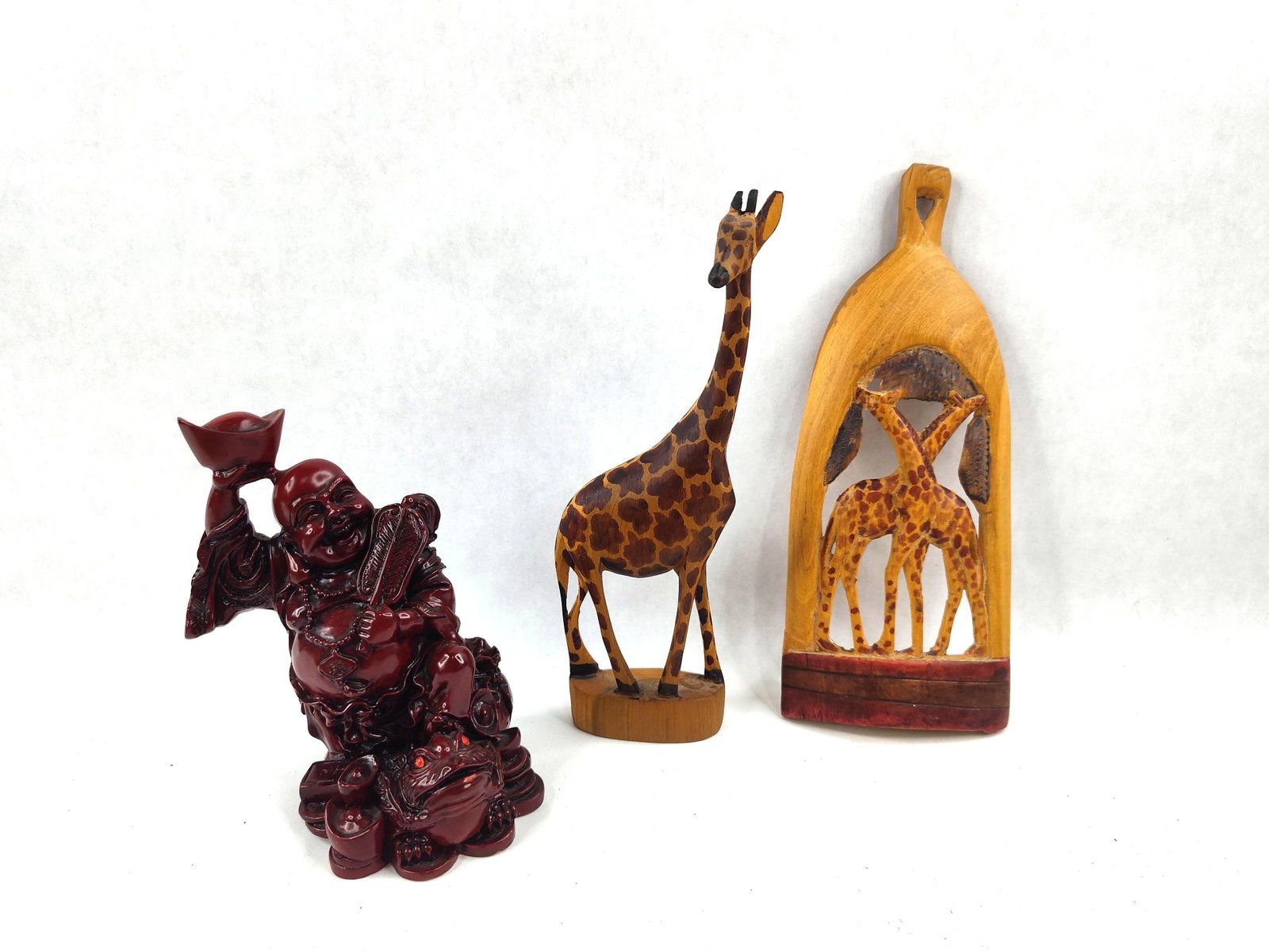 Resin Buddha & 2 Carved Wooden Giraffes: This lot features three decorative objects including a cast resin figurine and two hand-carved wooden items. The first item is a figurine of the Laughing Buddha (Budai) depicted in a seated