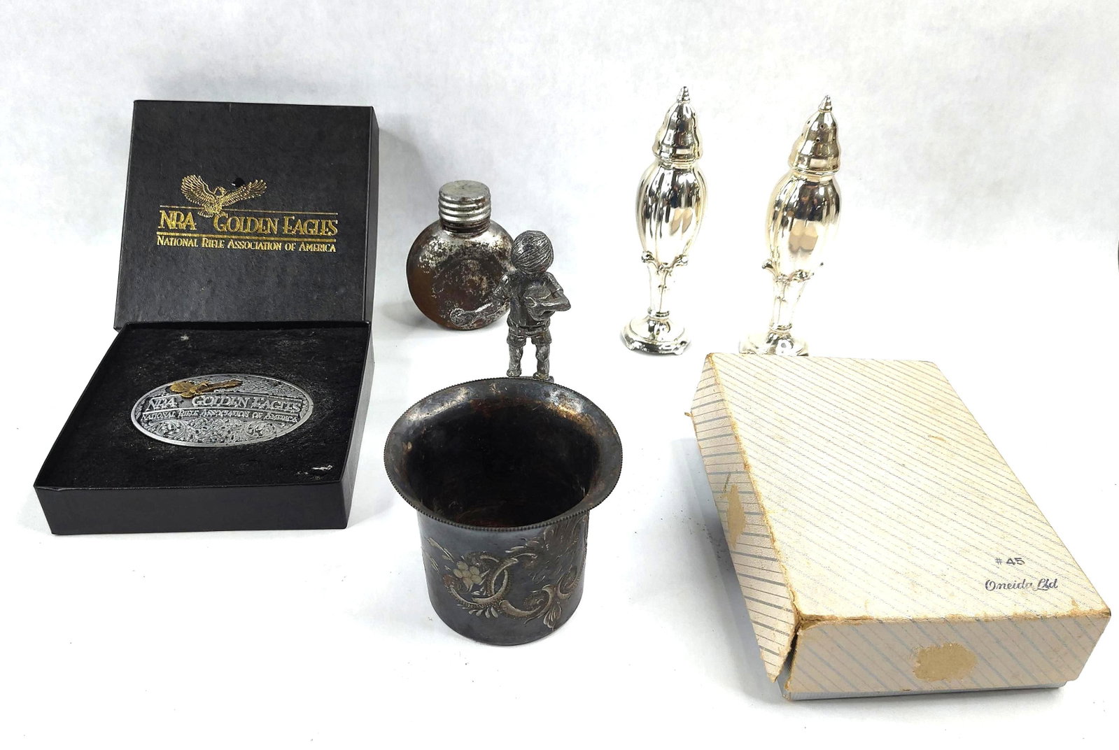 NRA Golden Eagles & Silver-Plated Group: A group of collectibles and silver-plated hollowware including a belt buckle, salt and pepper shakers, a cup, a flask, and a figurine. The lot features a 1994 Limited Edition NRA Golden Eagles belt