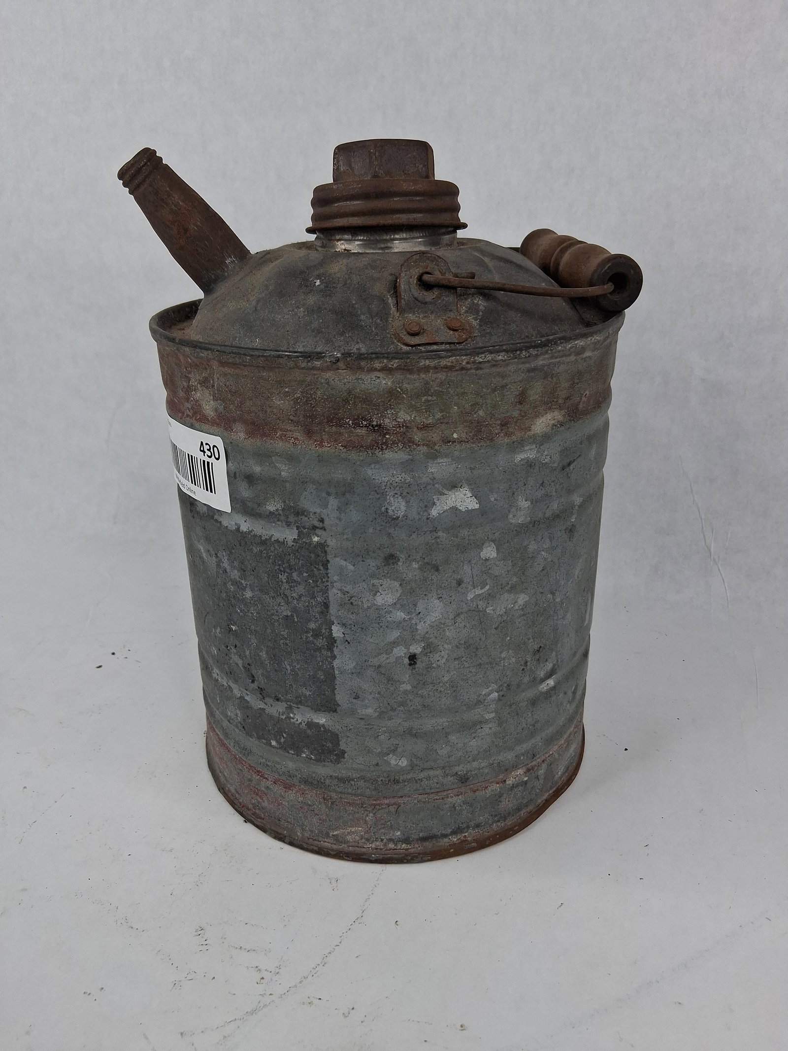 Fuel Can with Wooden Handle: This fuel or oil can features a galvanized steel body with a domed top and horizontal reinforcing ribs. The container is equipped with a wire bail handle featuring a turned wood grip for transport.