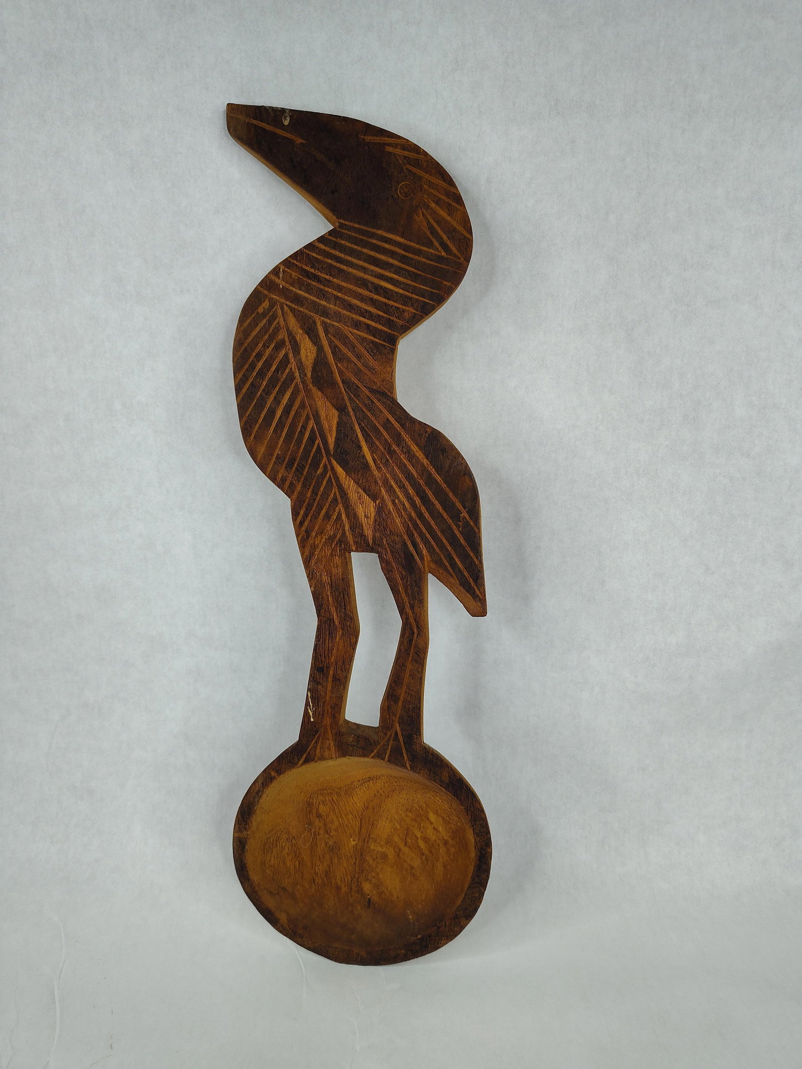 Malawi Carved Wood Crane Wall Plaque: Hand-carved wooden wall plaque from Malawi depicting a stylized crane in profile. The sculpture is crafted from a single piece of hardwood and stands atop a circular, shallowly concave base. The form 