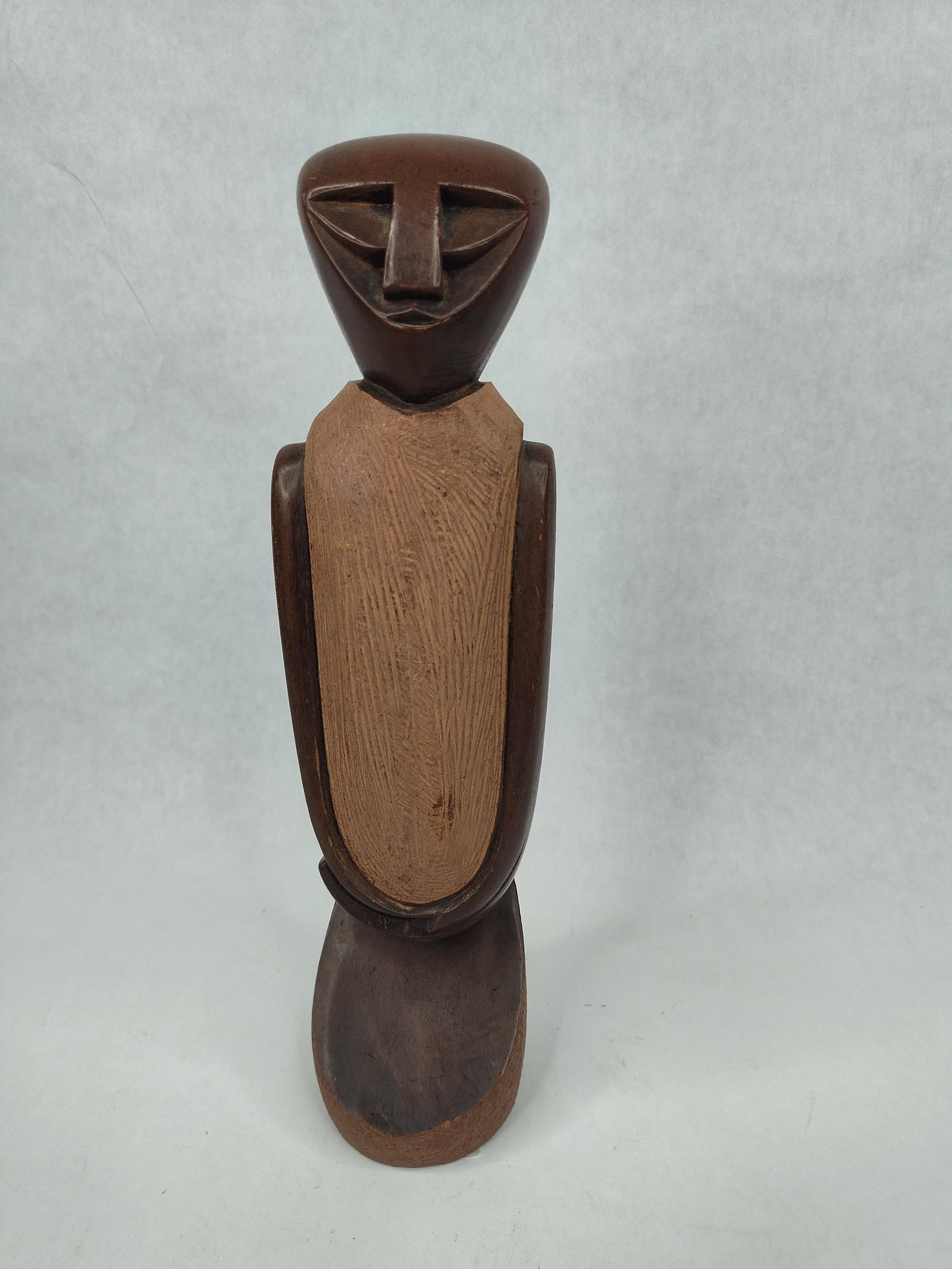 Modernist Carved Hardwood Humanoid: A modernist stylized humanoid figure carved from hardwood, exhibiting stylistic influences from African sculptural traditions. The sculpture features a highly geometric, triangular head with deeply