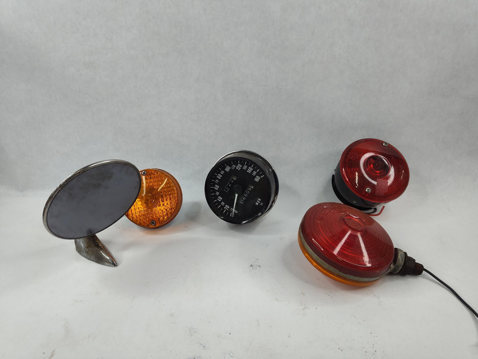 5 Vtg Nippon Seiki Speedometer & Parts: A lot of five motorcycle parts, likely dating from the 1960s to the 1970s. The primary component is a mechanical speedometer manufactured by Nippon Seiki. The speedometer face features a 0 to 160 mph