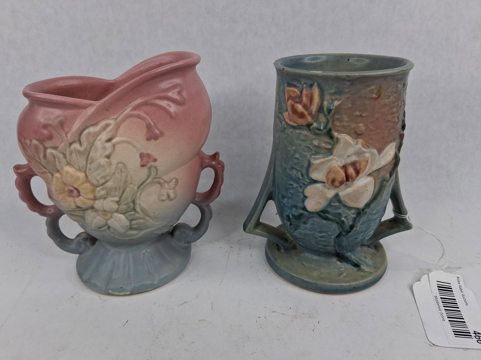 Pair Roseville & Hull Art Pottery Vases: This lot consists of two pieces of mid-20th-century American art pottery. The first is a Roseville Pottery vase in the Magnolia pattern, introduced in 1943. It features a cylindrical body with two dis