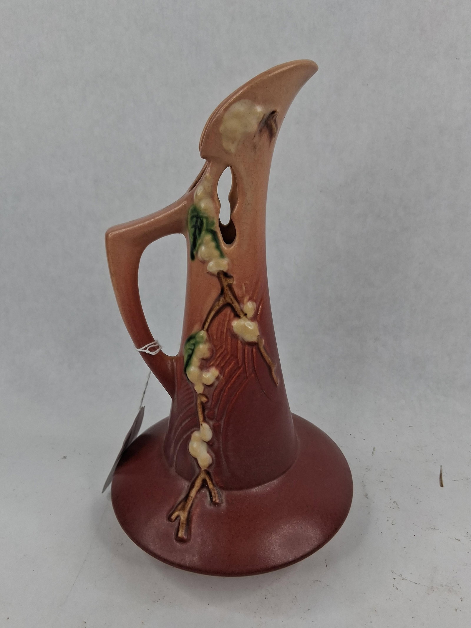 Roseville Snowberry Russet Ewer 178-10: An earthenware ewer-form vase produced by Roseville Pottery as part of the Snowberry line, introduced in 1947. The vessel features a wide, flared circular base tapering to a slender neck with an angul