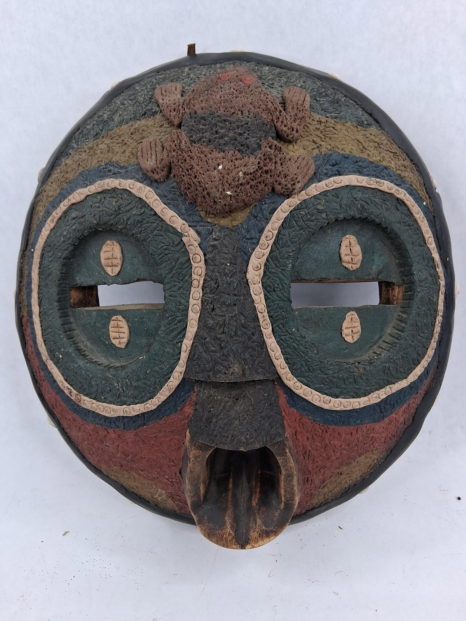 Novica Kunimdu Wood Mask w/ Relief Frog: This circular wooden mask is a contemporary handcrafted decorative piece from Ghana, known as the Kunimdu model. It is hand-carved from wood and finished with a thick, granular composition paste that 