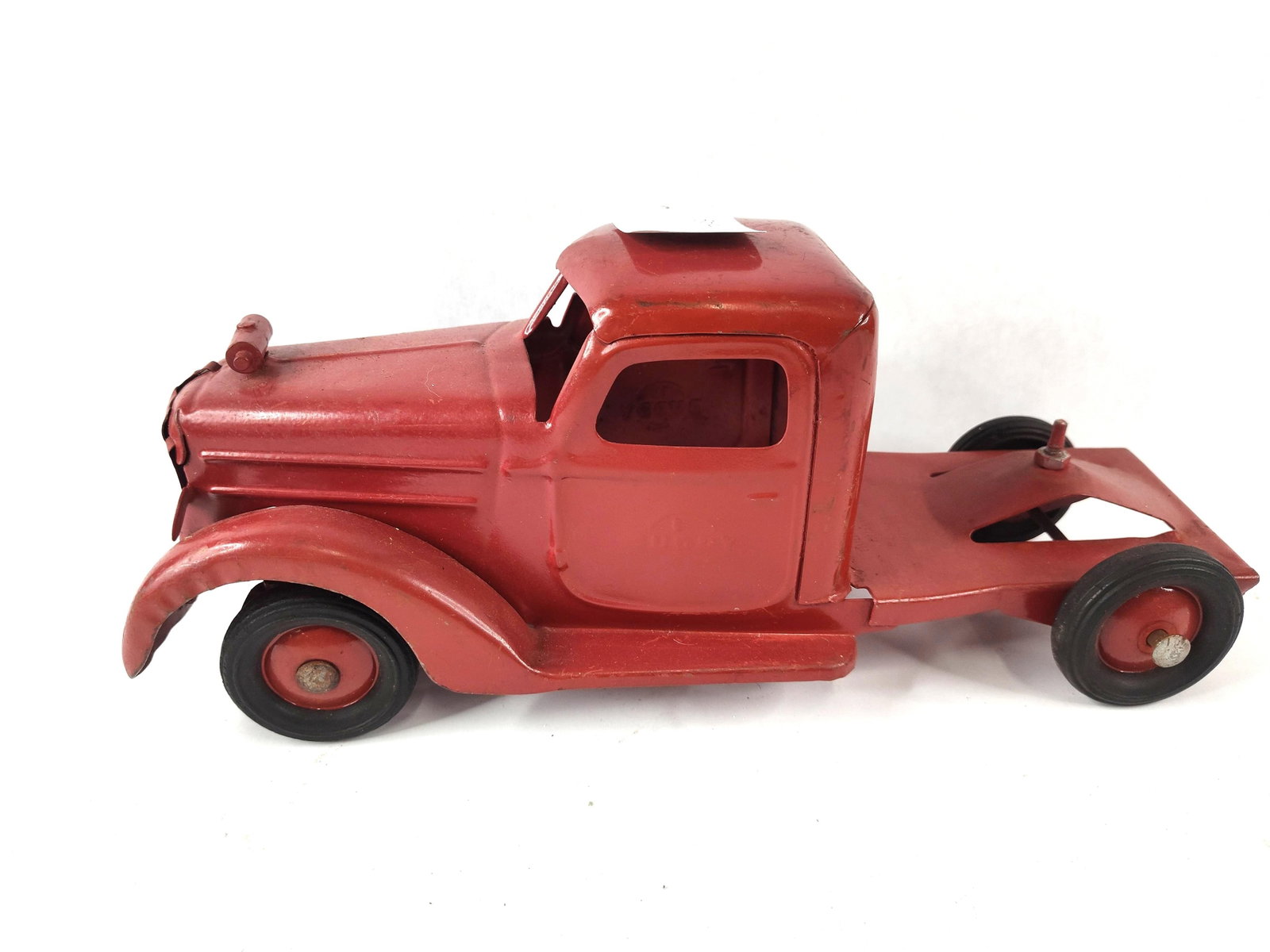 Buddy L Red Tractor Unit: This Buddy L tractor unit is constructed from pressed steel and features a manual push, free-rolling wheel mechanism. The cab doors are embossed with the manufacturer logo, featuring the name Buddy in