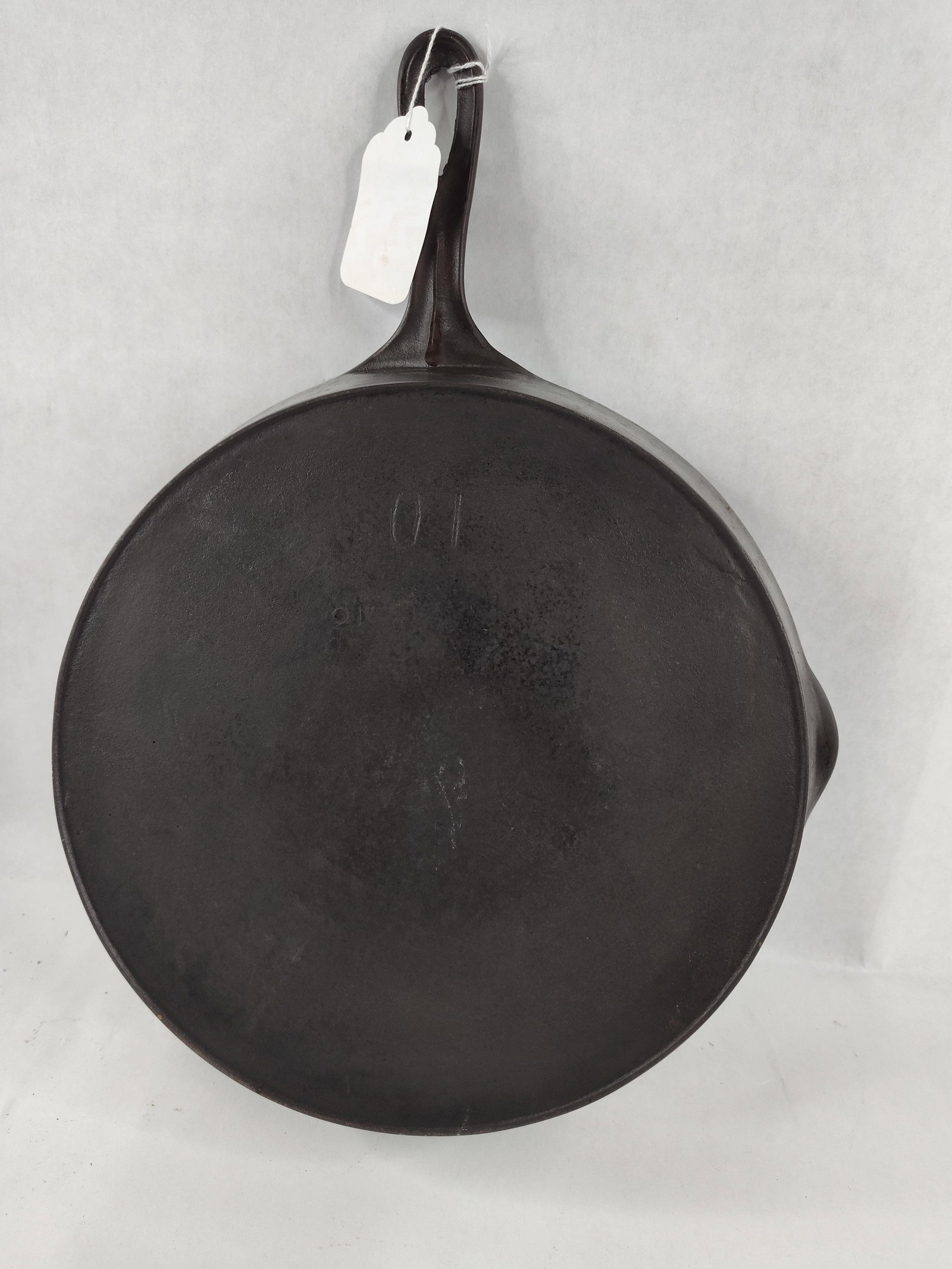 Japanese Cast Iron Skillet No. 10: A large cast iron skillet of Japanese origin. The skillet features a traditional round form with two integrated pour spouts and a tapered handle with a teardrop-shaped hanging hole. The construction
