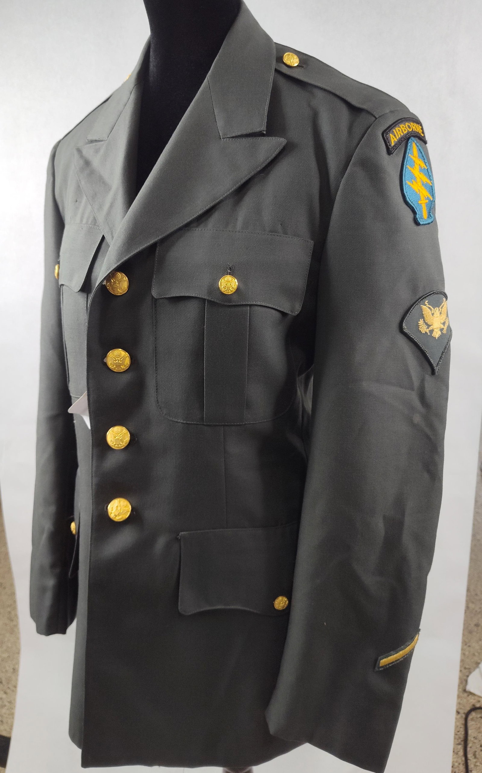 US Army Special Forces & Airborne Coat: A United States Army Service Dress Green (Class A) uniform coat, identified by the National Stock Number (NSN) 8405-01-105-6089 as a Men's Army Green Service Coat. The tunic is constructed from a