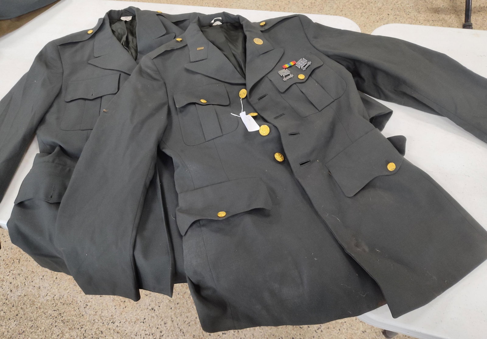 Pair U.S. Army Green Service Coats: A pair of authentic U.S. Army service uniform coats, designated as Army Green (Class A). These garments represent the standard service uniform utilized by the United States Army from the mid-1950s