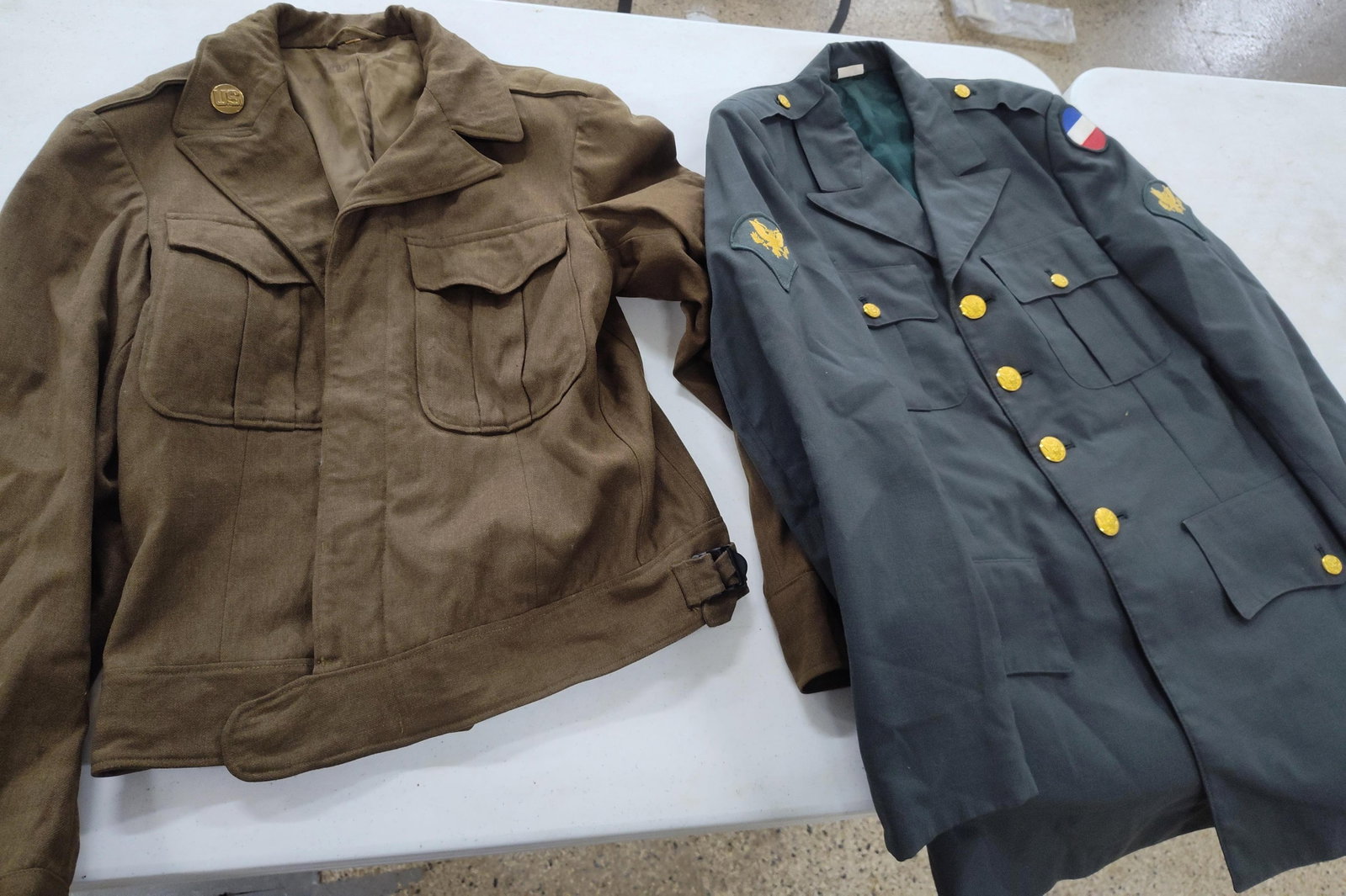 US Army WWII M-1944 & Cold War Jackets: This lot features two historical U.S. Army uniform jackets representing different eras of service. The first item is a World War II era M-1944 wool field jacket, commonly known as an Ike Jacket. This 