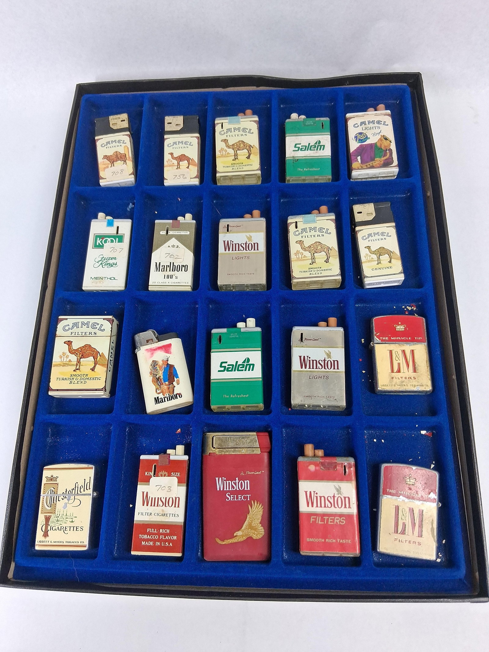 20 Vtg Tobacco Advertising Lighters: A collection of 20 vintage promotional cigarette lighters primarily featuring American tobacco brands, organized in a blue velvet-lined display tray. The set includes a variety of construction