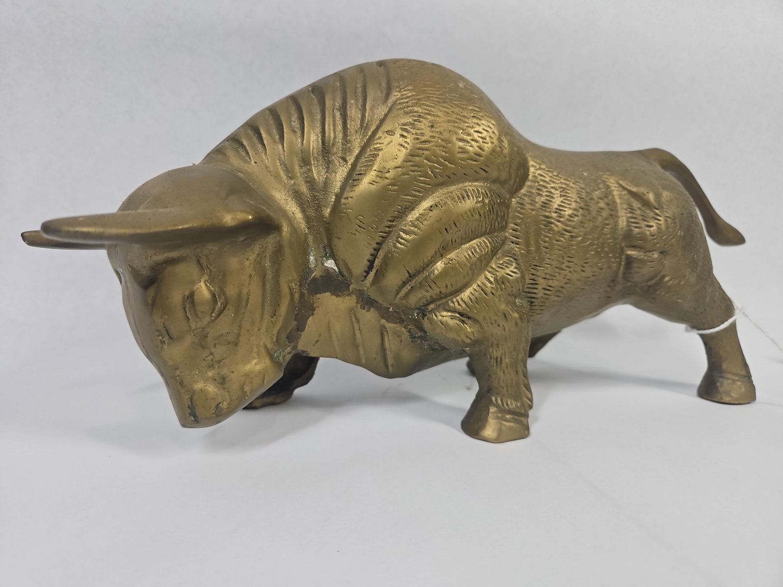 Mid-C. Modern Cast Brass Charging Bull: This cast brass figurine depicts a charging bull in a muscular, stylized pose with its head lowered and tail arched. The piece is constructed from solid brass and features a textured surface intended