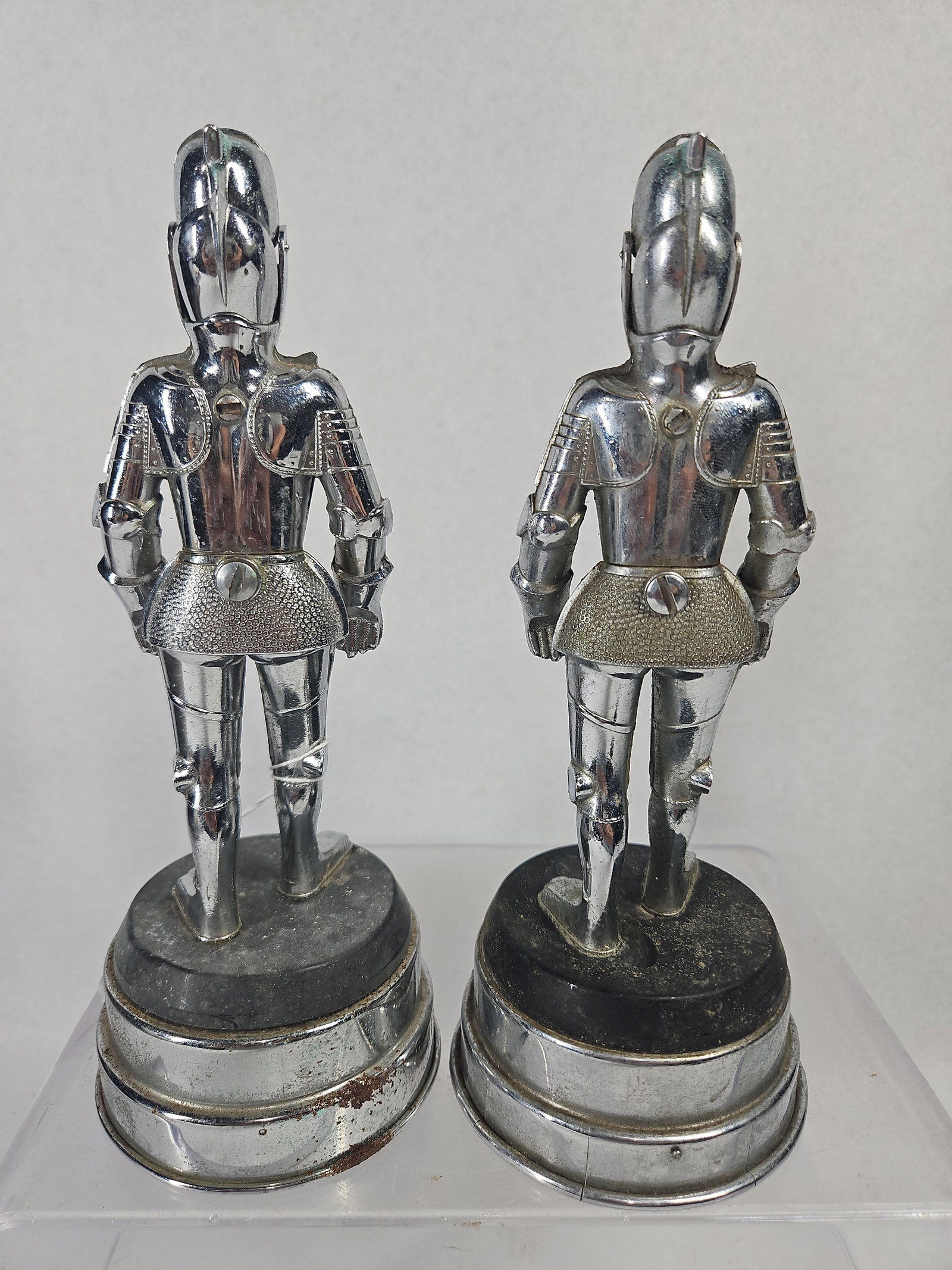 Pair Vtg Chrome Figural Knight Lighters: A pair of vintage table lighters constructed from chrome-plated metal, designed as knights in standing suits of armor. Each figure is modeled with a close-helmet, breastplate, pauldrons, and