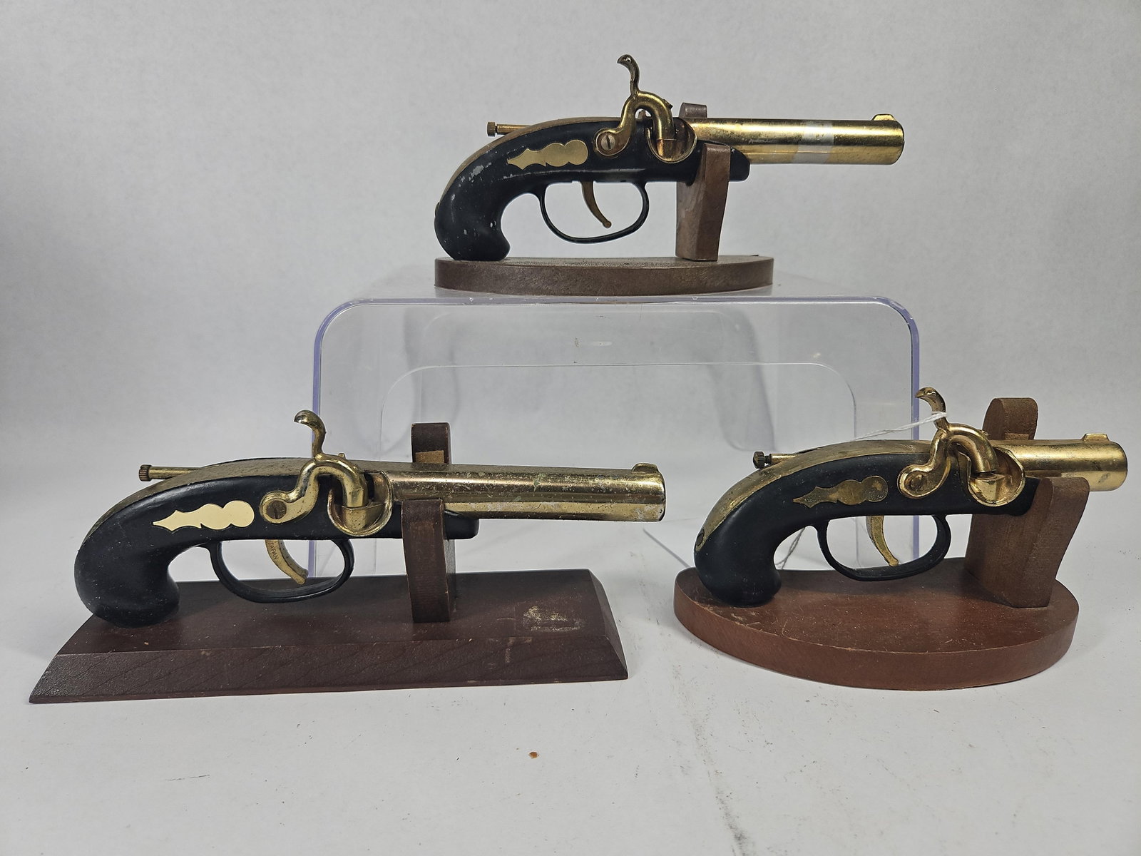 3 Japanese Percussion Pistol Lighters: A Japanese trio of miniature novelty cigarette lighters designed in the form of mid-19th-century percussion cap pocket pistols. The lighters are constructed with brass-toned metal alloy barrels,