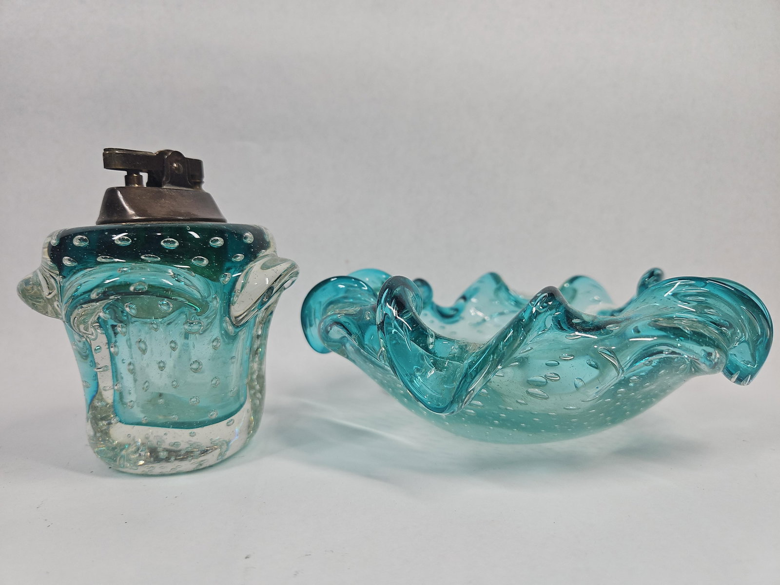 Pair Turquoise Bullicante Glass Smokers: A two-piece smoking set consisting of a table lighter and a matching ashtray, both crafted in turquoise and clear art glass. The pieces are executed with the bullicante technique, featuring a dense