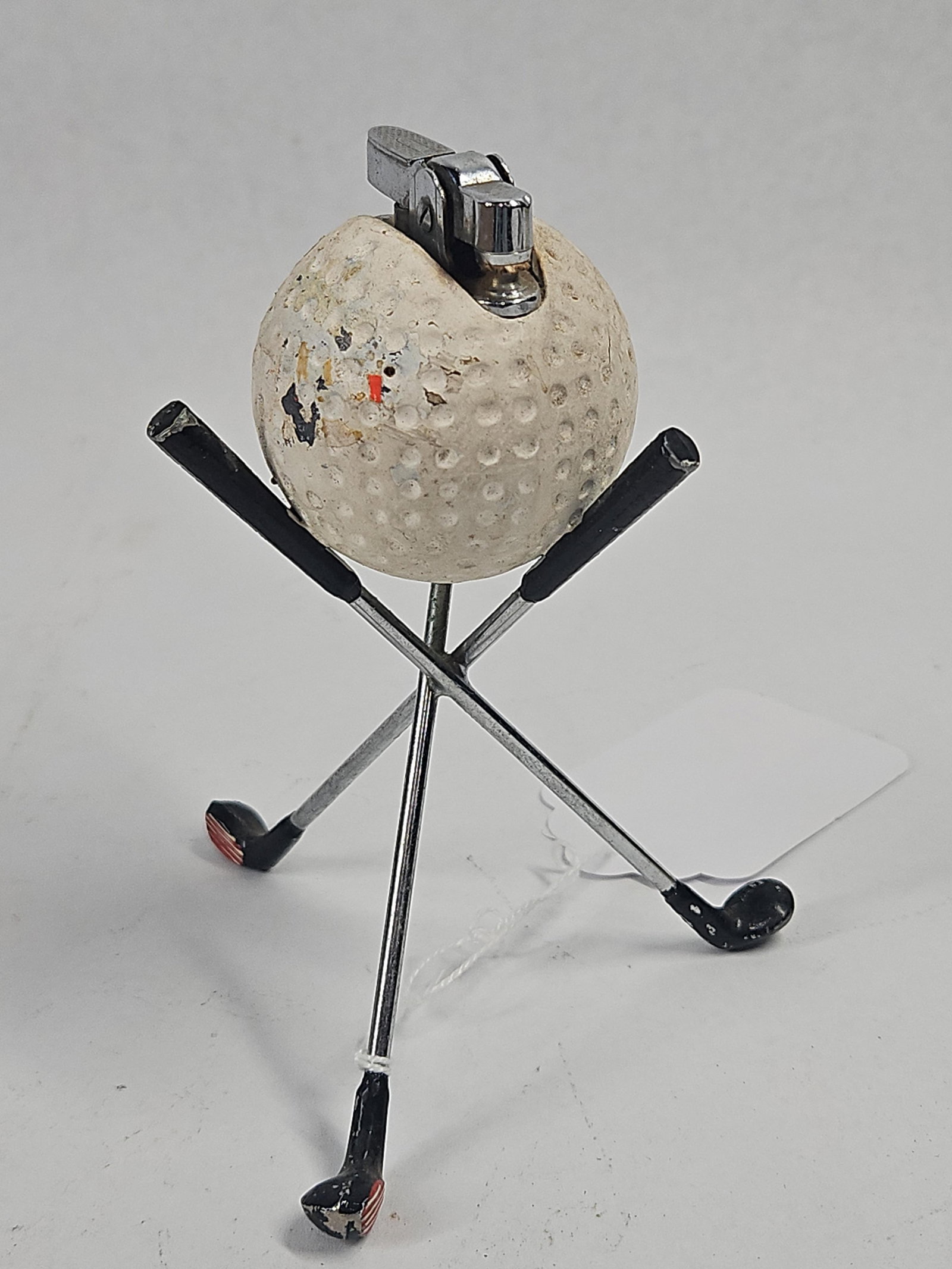 Vtg Golf Ball Lighter w/ Club Stand: A mid-century novelty table lighter featuring a golf ball body supported by a miniature club tripod stand. The white dimpled ball contains a chrome-finished lighter insert at the crown. The supporting
