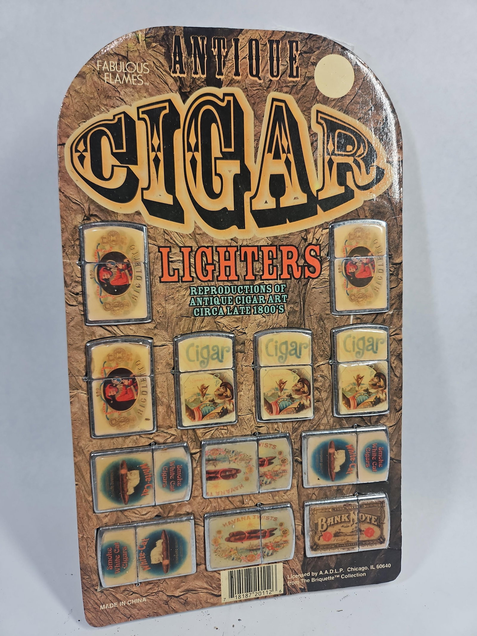 Briquette Collection Cigar Art Lighters: A collection of flip top windproof lighters mounted on an original point of sale retail display card. The set is titled Antique Cigar Lighters and marketed under the Fabulous Flames brand name. Each