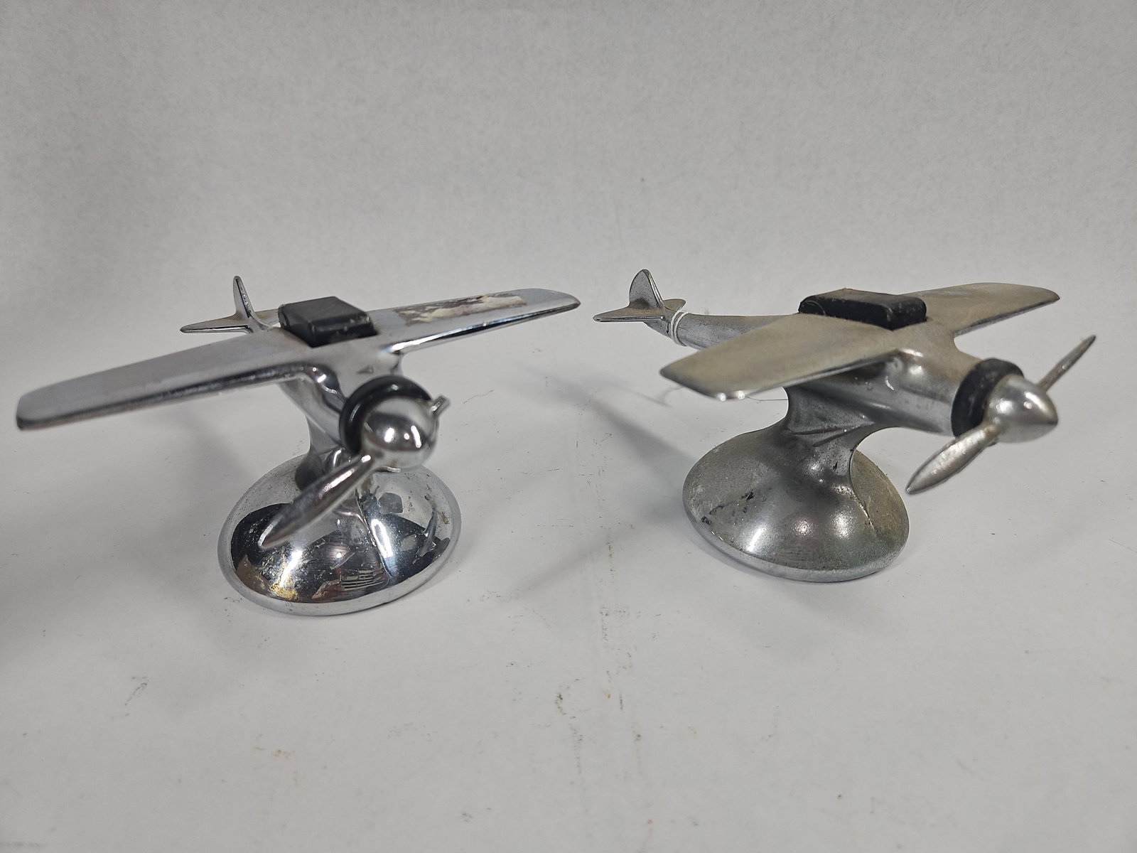 Pair Art Deco Chrome Monoplane Lighters: A pair of American Art Deco table lighters designed in the form of stylized monoplanes. Each item is manufactured from chrome-plated cast metal and features a high-wing configuration, a two-blade