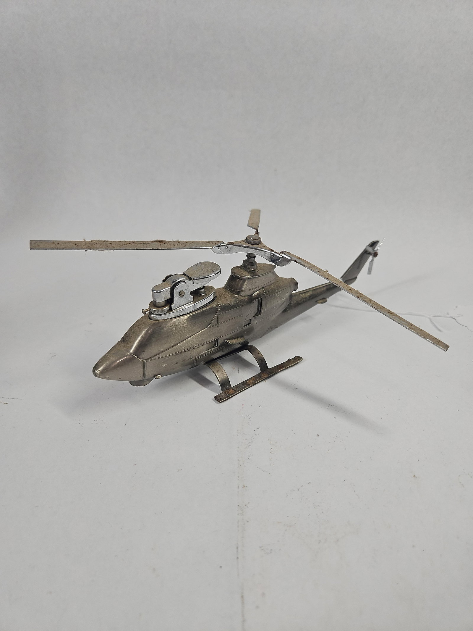 Japanese Metal Huey Cobra Table Lighter: A Japanese table lighter designed in the form of a Bell AH-1 HueyCobra attack helicopter. The piece is constructed from cast silver-toned base metal with chrome-plated components. The model features