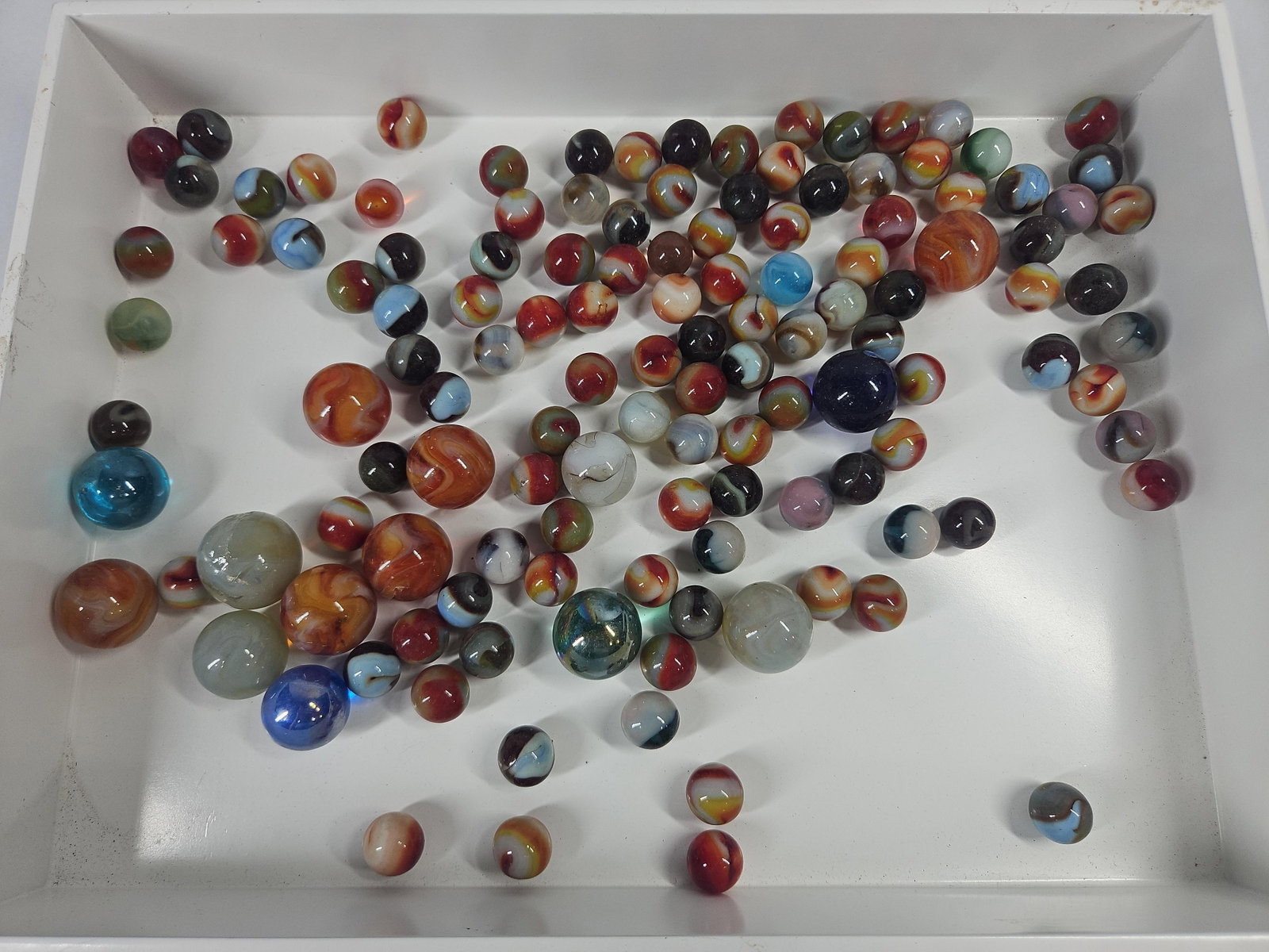 Vtg Machine-Made Glass Marbles w/ UV: An assortment of vintage machine-made glass marbles featuring a variety of sizes and patterns. The items are constructed from opaque, translucent, and transparent glass. Patterns present within the gr