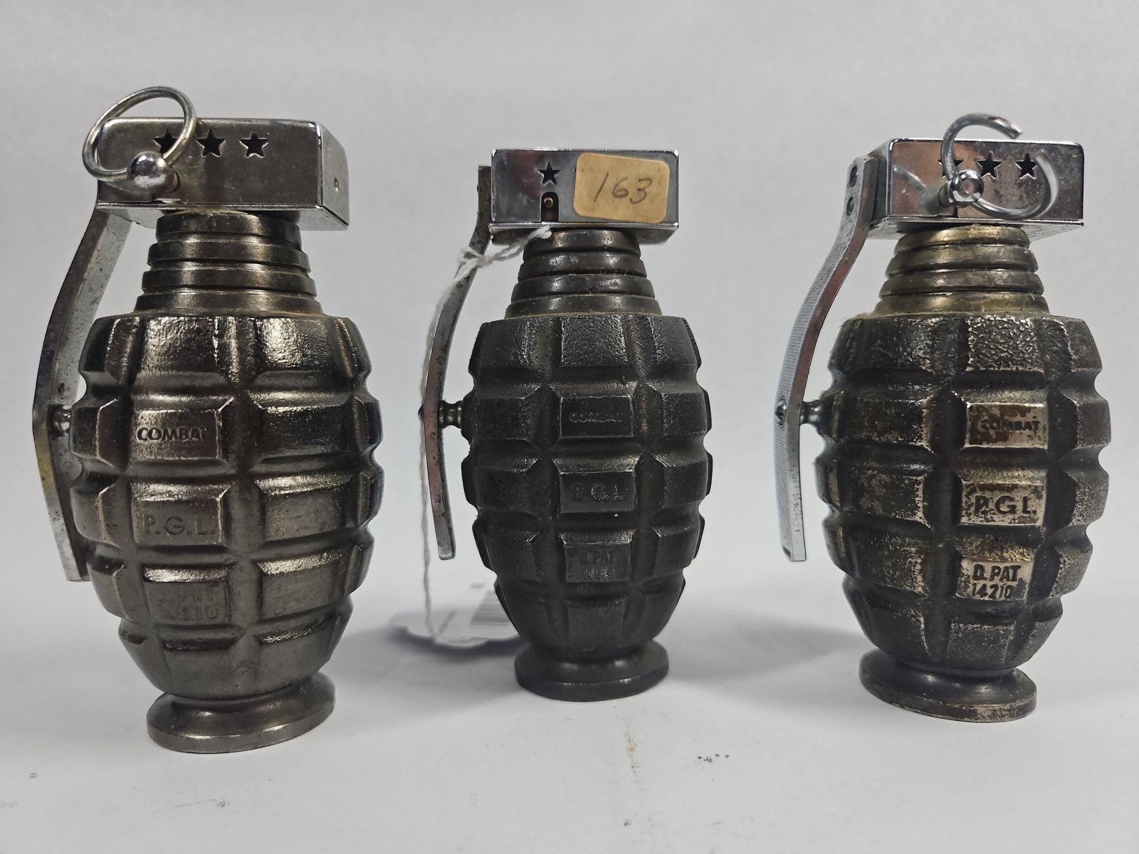 3 P.G.L. Combat Grenade Table Lighters: This set consists of three matching novelty table lighters modeled after Mk 2 "pineapple" hand grenades. Each item features a cast metal body with an antiqued dark silver-tone finish and a textured