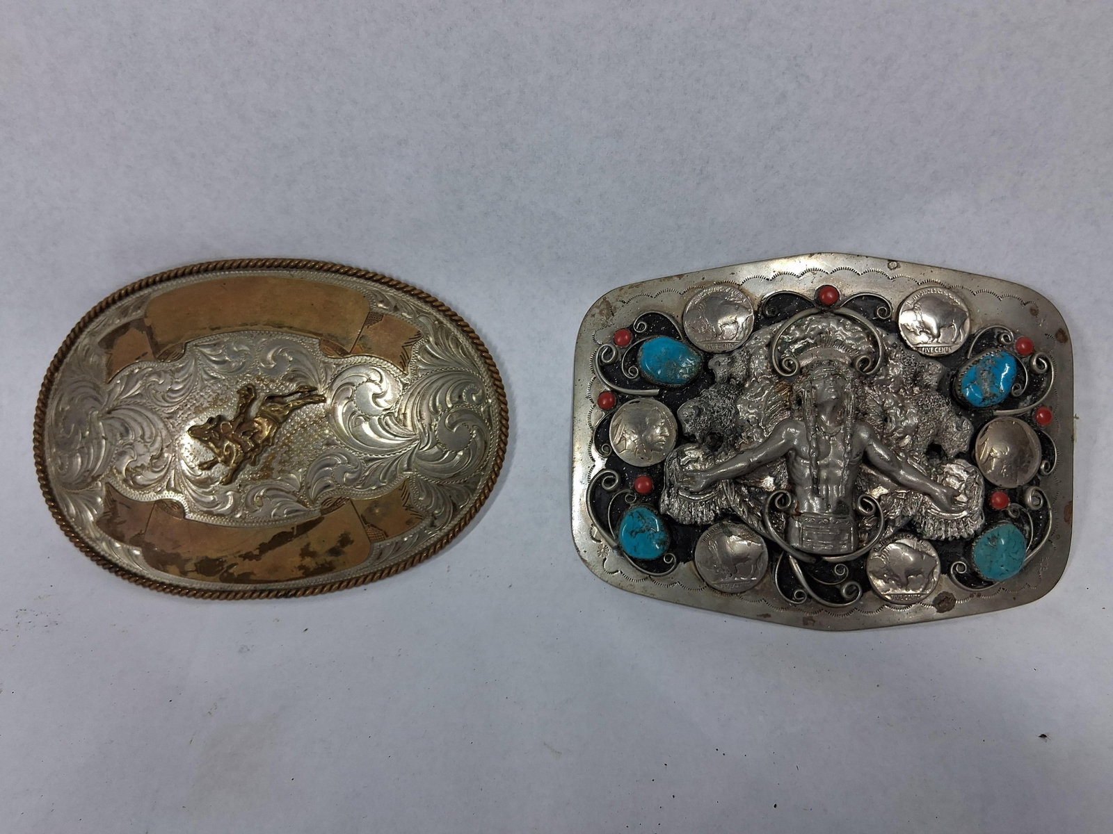 Pair Montana Silversmiths Rodeo Buckles: This lot consists of two vintage Western-themed belt buckles. The first is an American-made oval buckle produced by Montana Silversmiths, crafted from nickel silver with a rope-twist border and