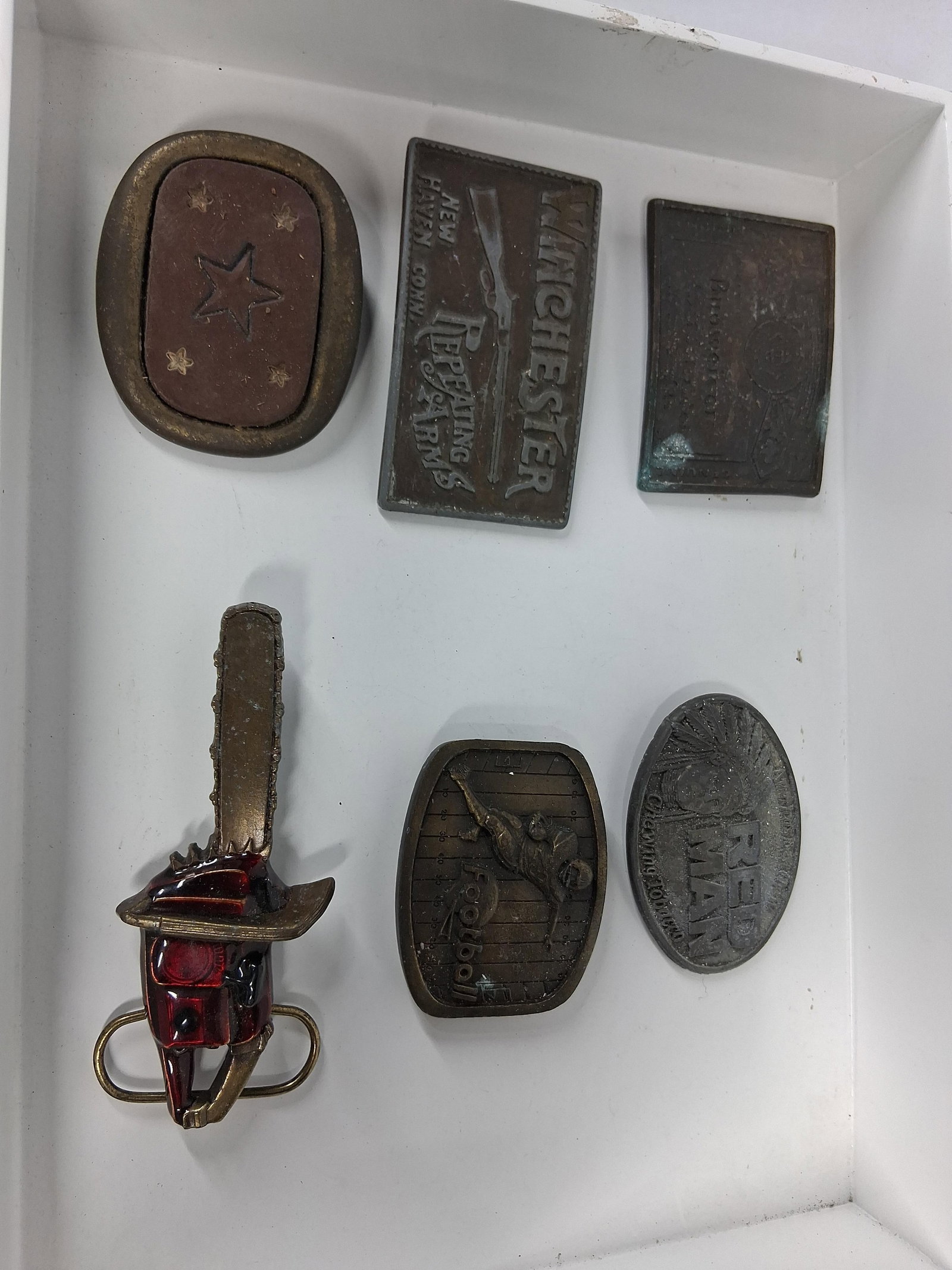 6 Vtg Cast Metal Advertising Buckles: An assortment of six vintage cast metal belt buckles featuring various advertising, sports, and novelty themes. The lot includes three advertising pieces: a rectangular buckle depicting a