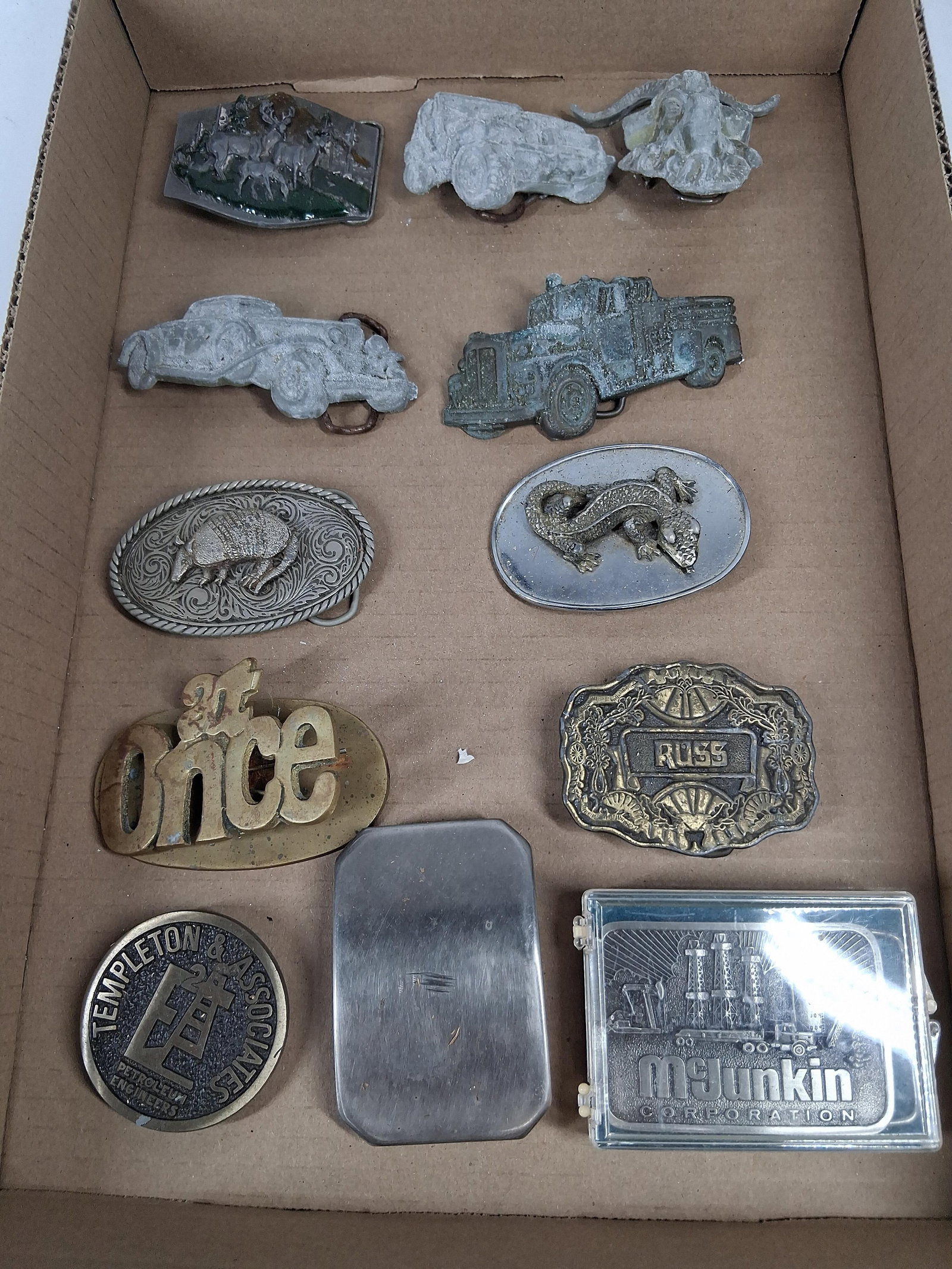 12 Vtg Siskiyou & Great American: A collection of twelve vintage American and unbranded collectible belt buckles featuring various wildlife, automotive, and industrial subjects. A rectangular white metal buckle features a relief scene