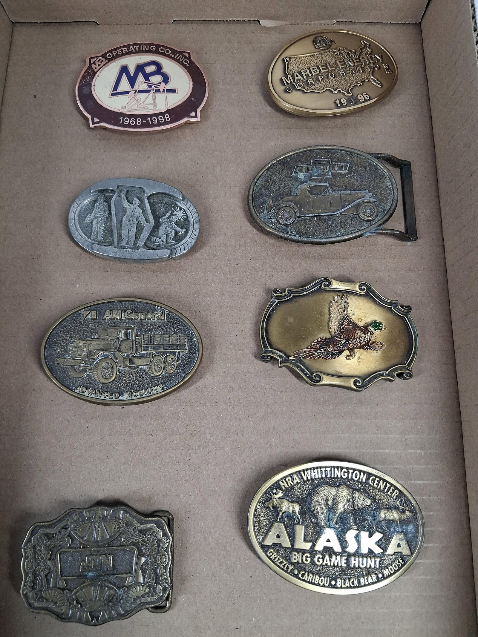 Set 8 Vtg Chevy, AM & NRA Belt Buckles: An assortment of eight vintage belt buckles constructed from various metals including brass-toned, silver-toned, and copper-toned alloys, some featuring enamel accents. The collection includes corpora