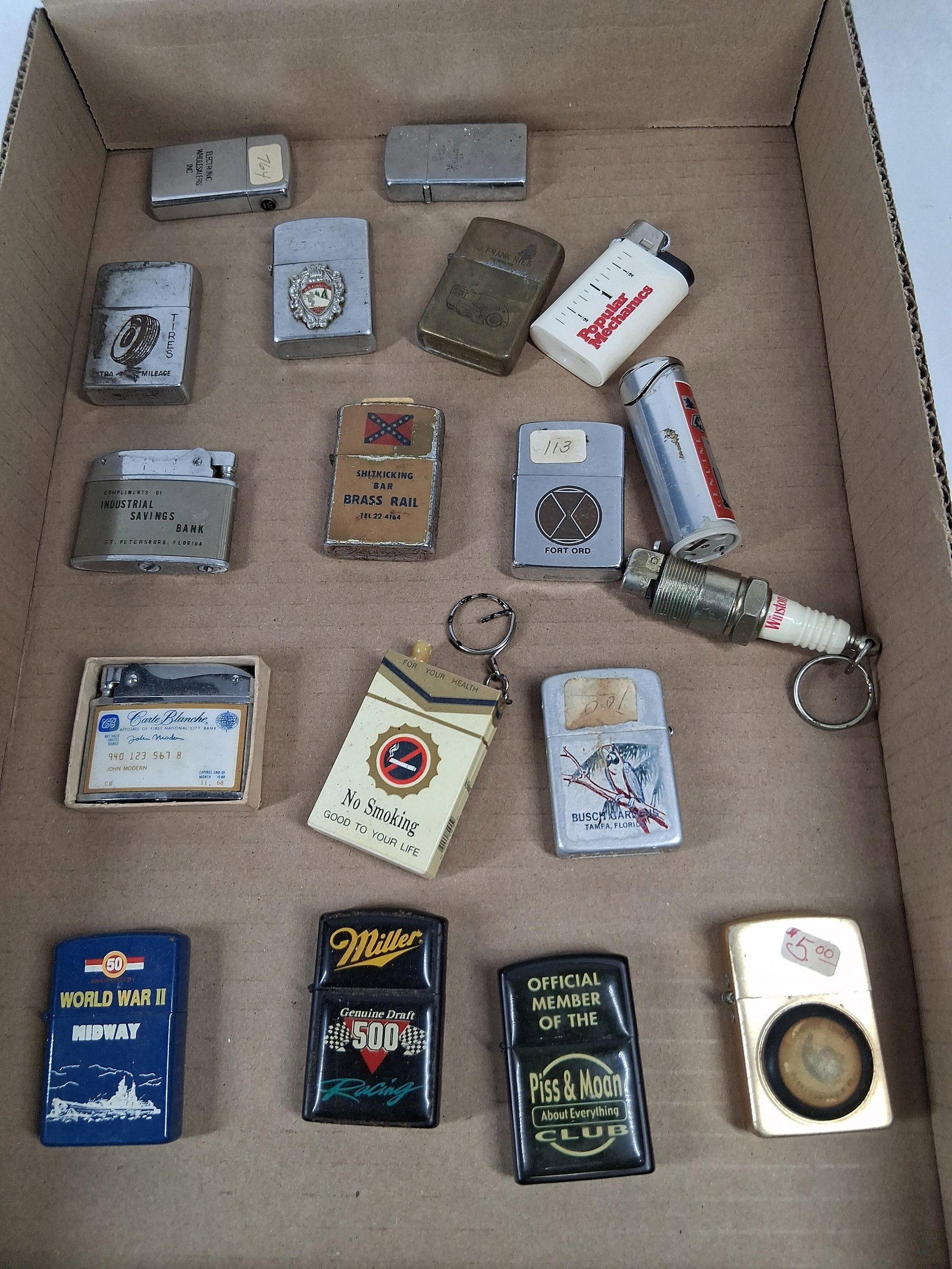 Zippo, Advertising & Military Lighters: An assortment of vintage pocket lighters and novelty smoking accessories featuring various advertising, military, and commemorative themes. The collection includes several genuine Zippo brand