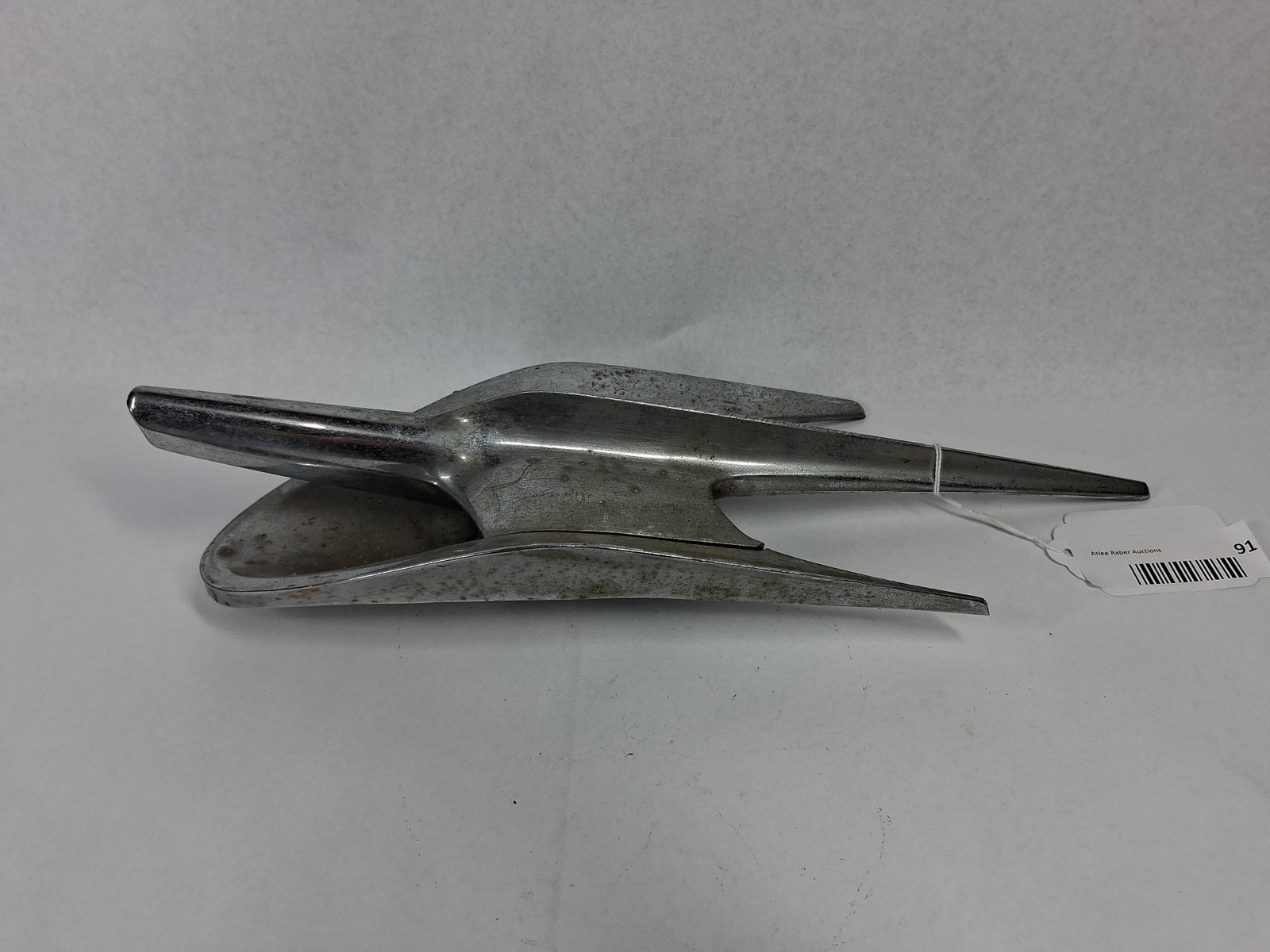 1954 Ford Hood Ornament Assembly: A two-piece chrome-plated cast metal hood ornament assembly produced by the Ford Motor Company for 1954 passenger vehicles. The assembly features a stylized swept-wing jet plane design. The underside