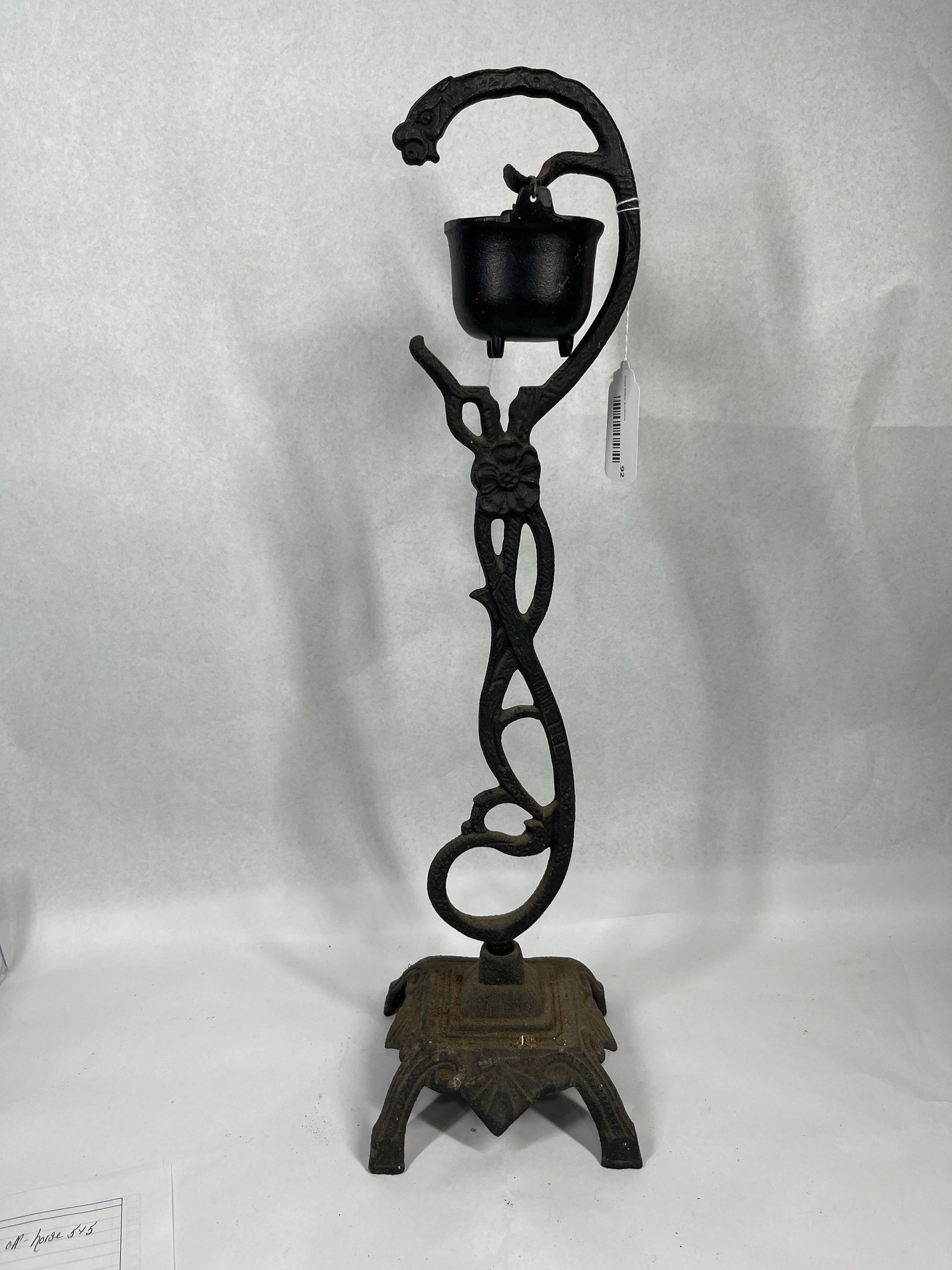 39) includes all of these but replaces: A decorative cast iron hanging cauldron stand with a matching miniature pot. The assembly is constructed using sand-casting techniques, resulting in a characteristic textured surface throughout. The