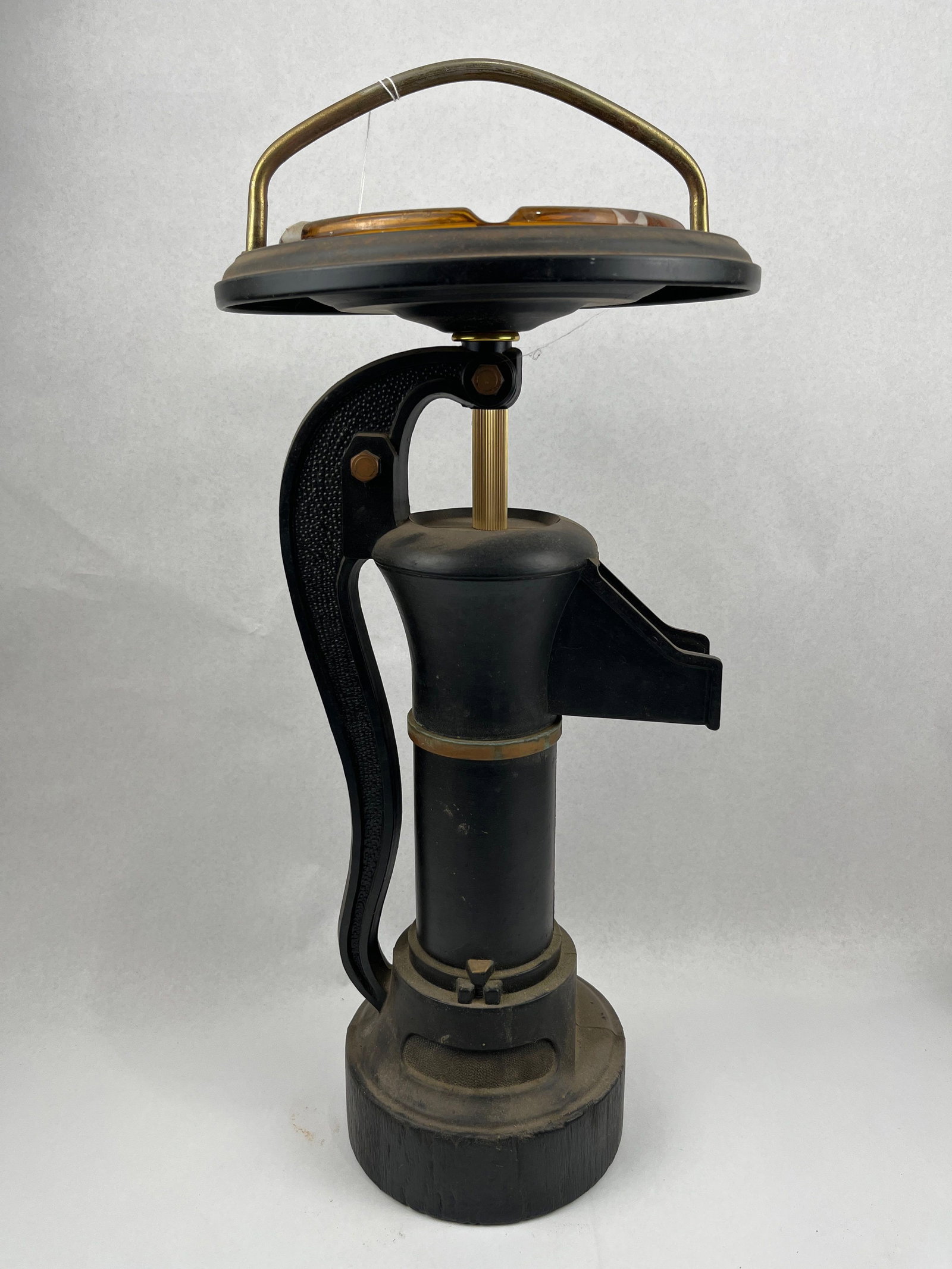 Vtg Cast Metal Water Pump Ashtray Stand: A mid-century decorative ashtray stand designed in the form of a vintage manual water pump. The main body of the pump is constructed from cast metal with a textured black finish. It features