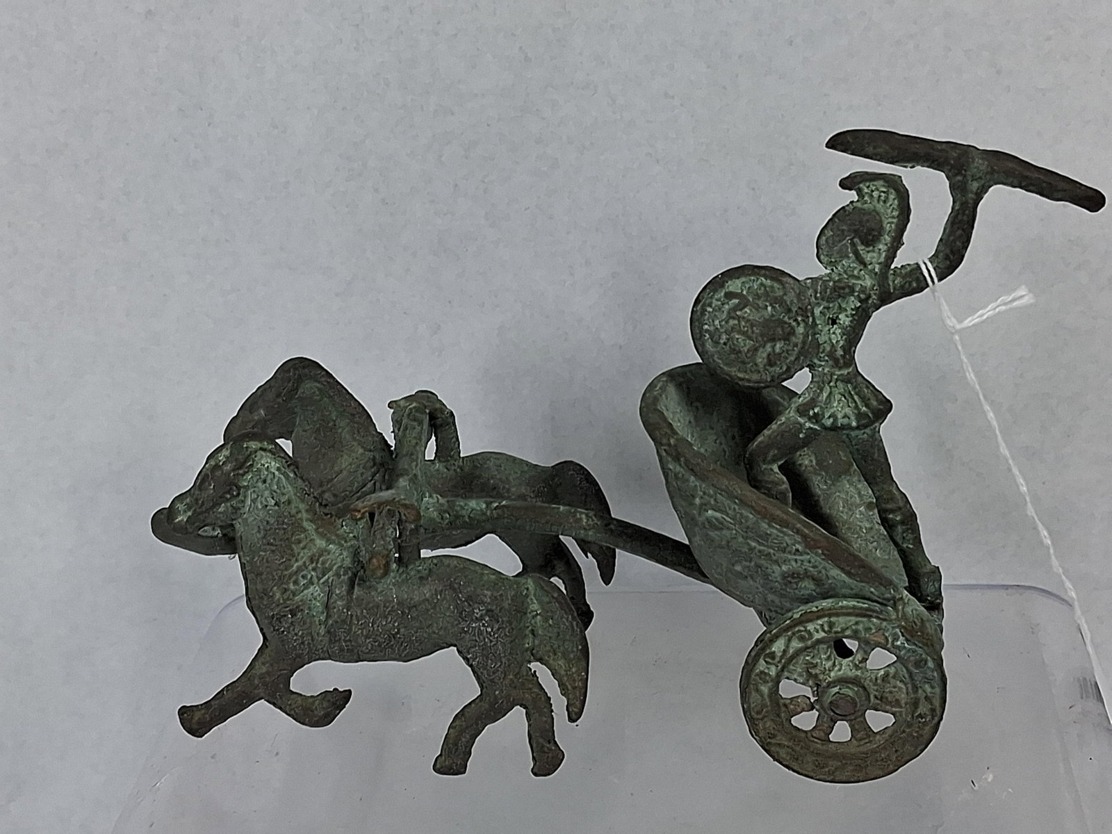 Cast Bronze Classical Warrior & Chariot: A cast bronze sculpture depicting a classical warrior standing within a biga, or two-horse chariot. The figure is portrayed in a dynamic combat pose, wearing a crested helmet, a short tunic, and