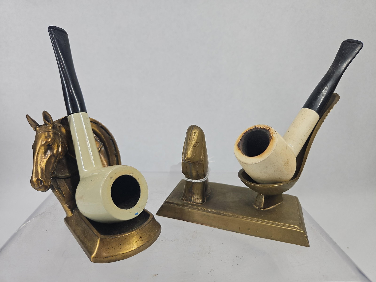 Vtg Venturi & D.E. Color Pipes w/Stands: This lot consists of two vintage smoking pipes and two decorative brass stands. The first pipe features a cream-colored bowl and shank with a black stem. An impressed mark on the side of the shank