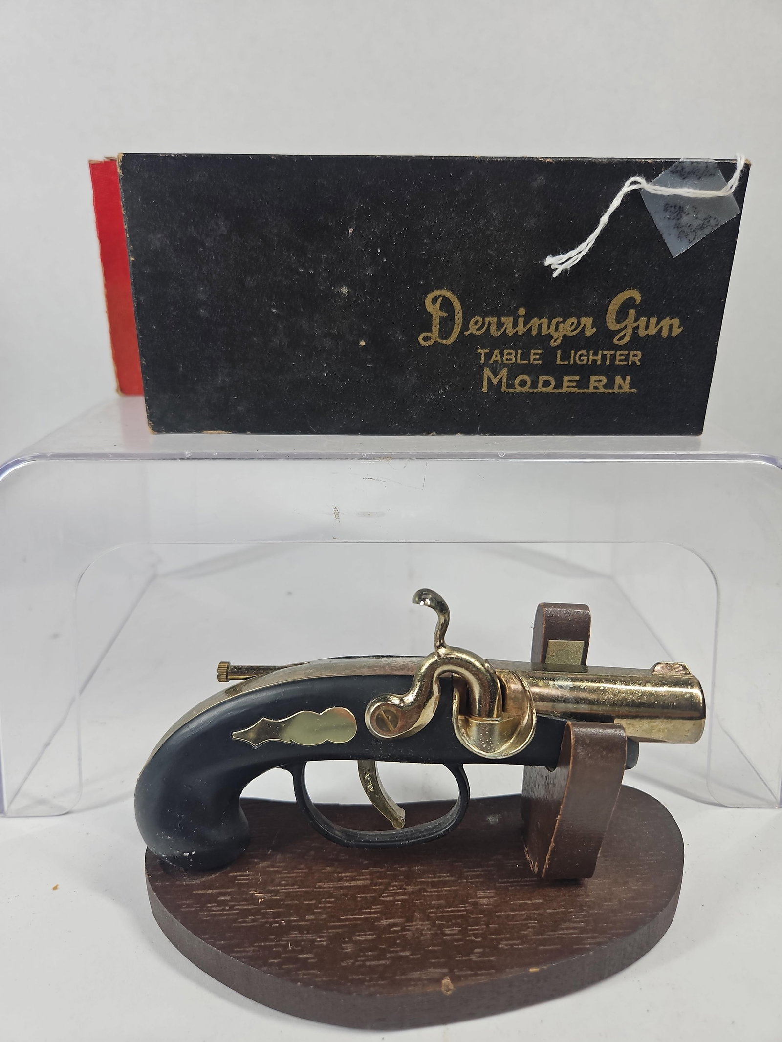 Japan Derringer Style Table Lighter: A Japanese novelty table lighter modeled after a percussion Derringer pistol. The lighter features a black finished body constructed of composite or metal, accented with a brass toned barrel, hammer, 