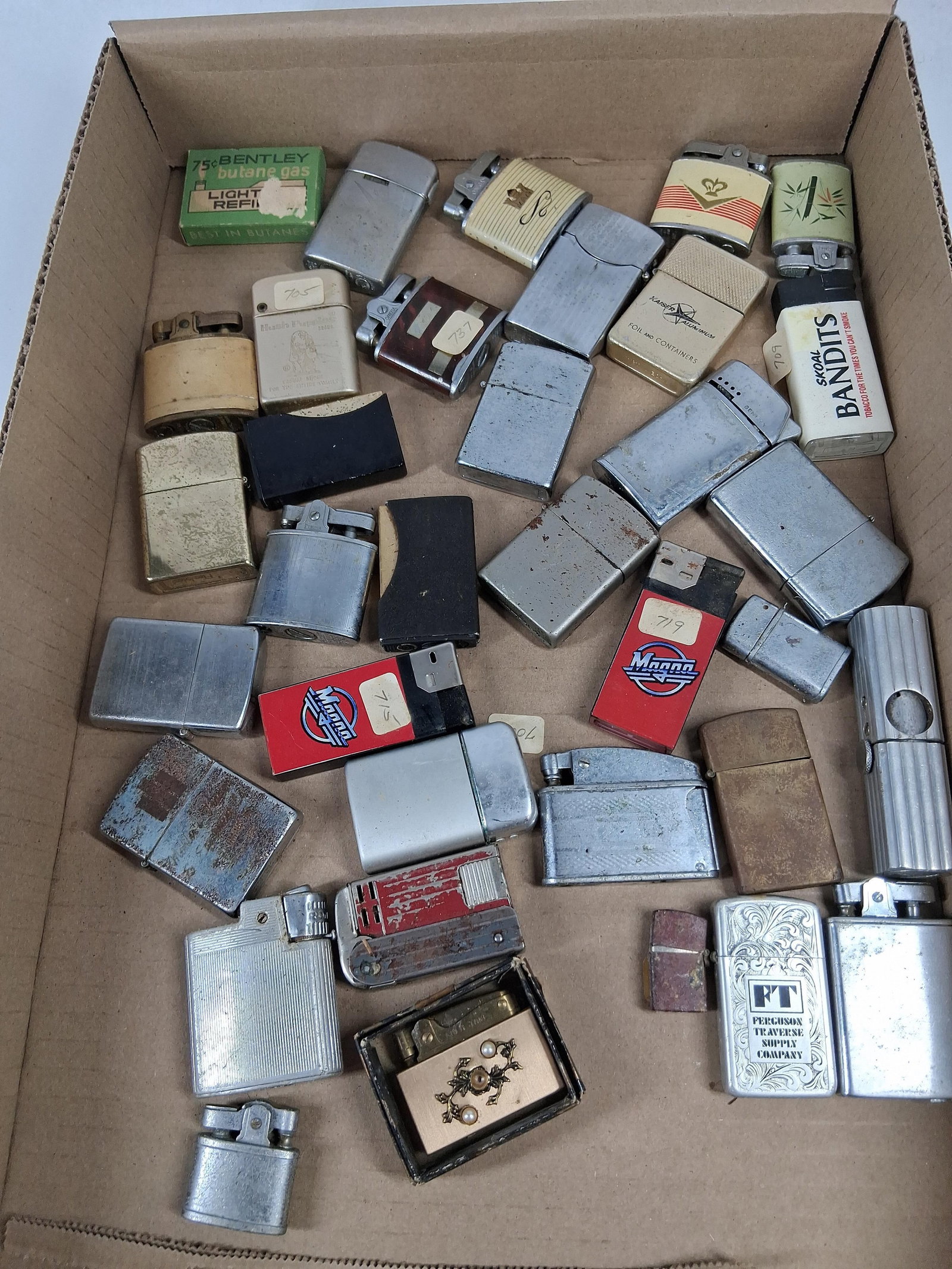 Storm Master, Penguin, Bentley Lighters: A collection of vintage pocket lighters in various styles, including automatic, flip-top, and butane models. The pieces are constructed from chrome-plated metal, brass-toned metal, and plastic. One si