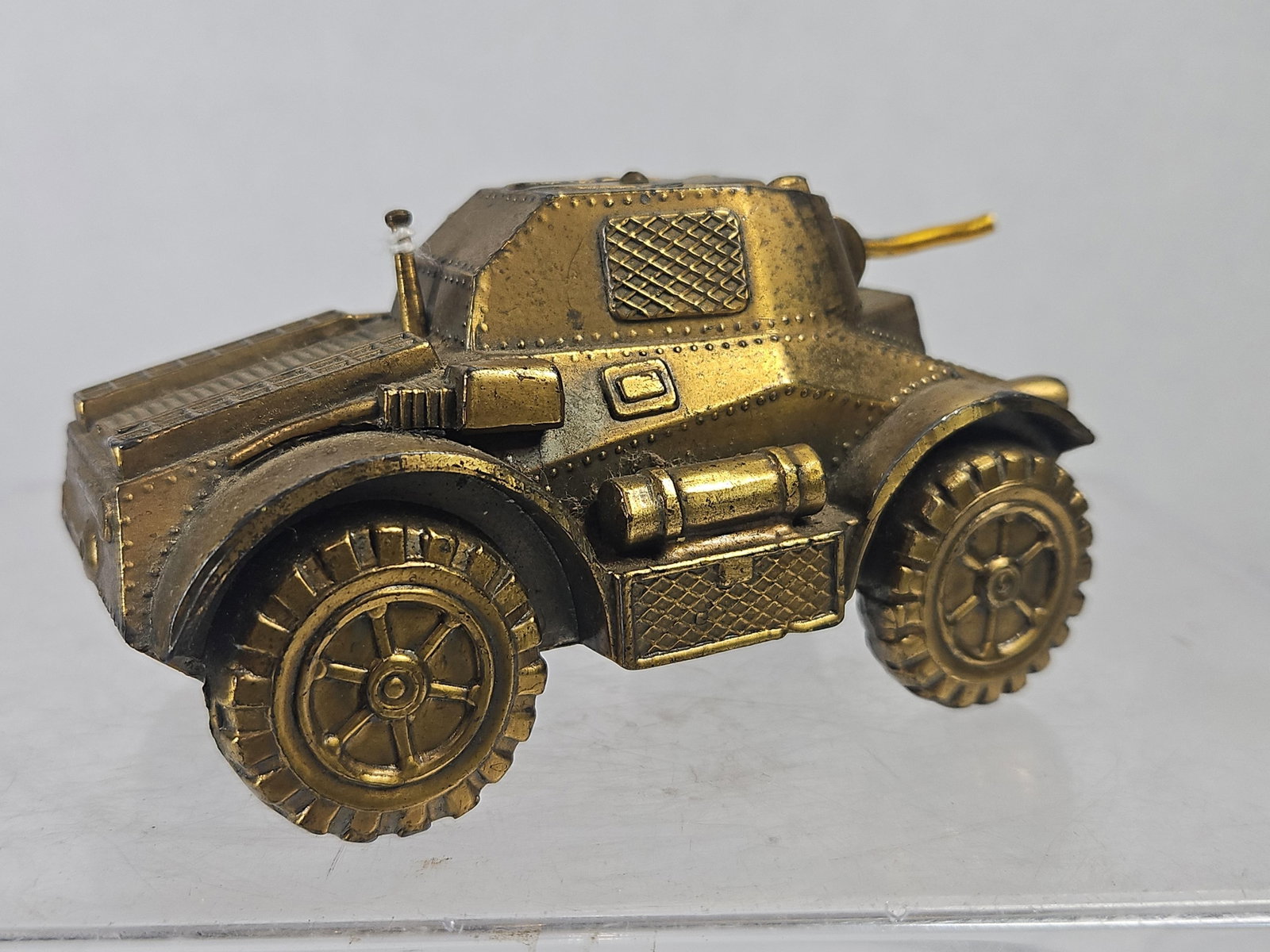 Japanese Armored Vehicle Table Lighter: A Japanese figural table lighter in the form of a four-wheeled armored scout vehicle, constructed from gold-tone plated die-cast metal. The vehicle features molded details including riveted armor