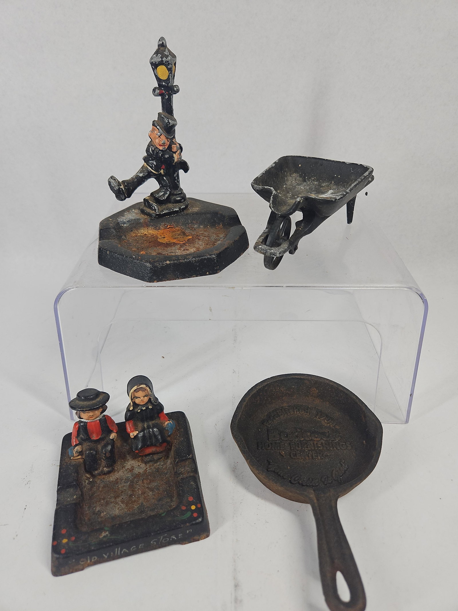 Badcock Skillet & Cast Iron Miniatures: A collection of painted cast iron miniature items and novelties. The assortment includes two figural ashtrays, one depicting a man in a top hat leaning against a lamp post and another rectangular