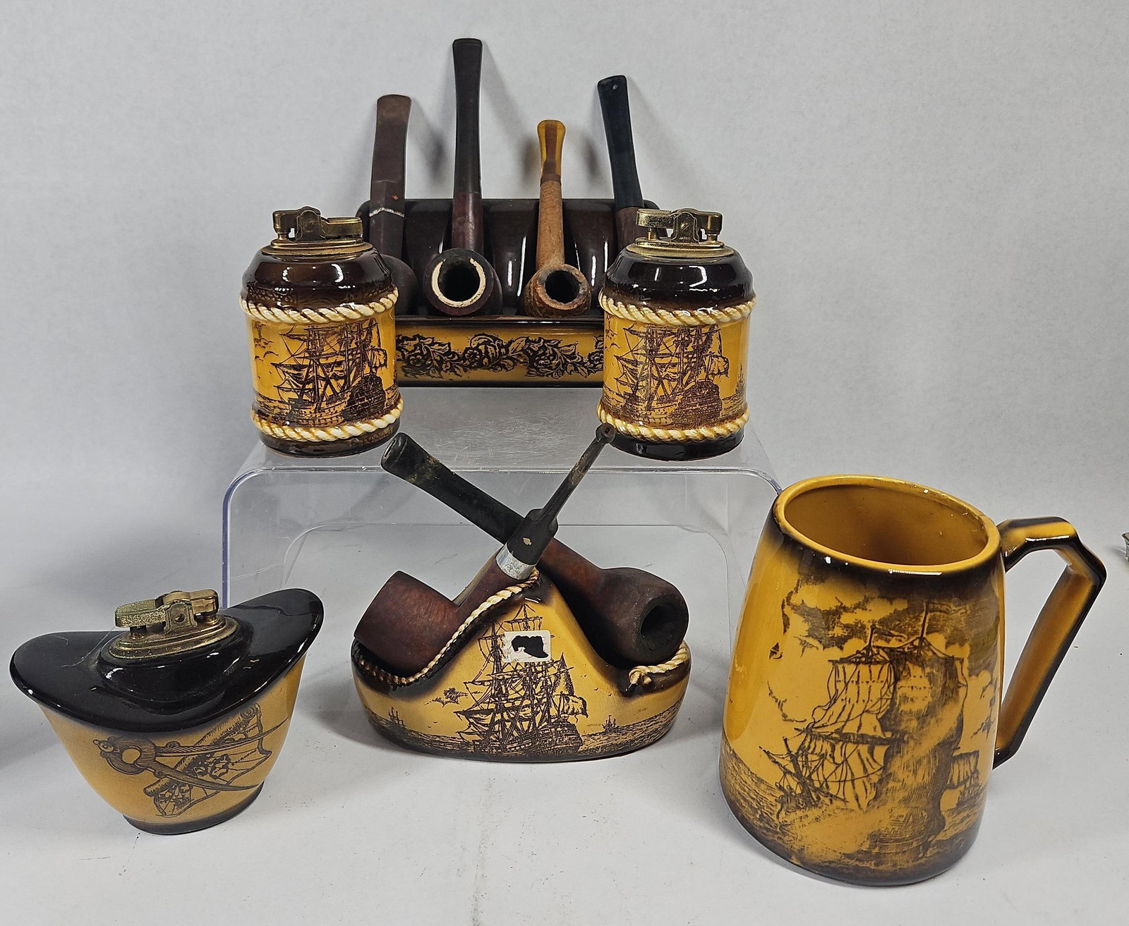 Wales Japanese Nautical Ceramic Pipes: A group of Japanese ceramic smoking accessories and a mug featuring a nautical motif. The ceramic pieces are finished in a mustard-yellow glaze with dark brown glazed accents at the rims and bases.