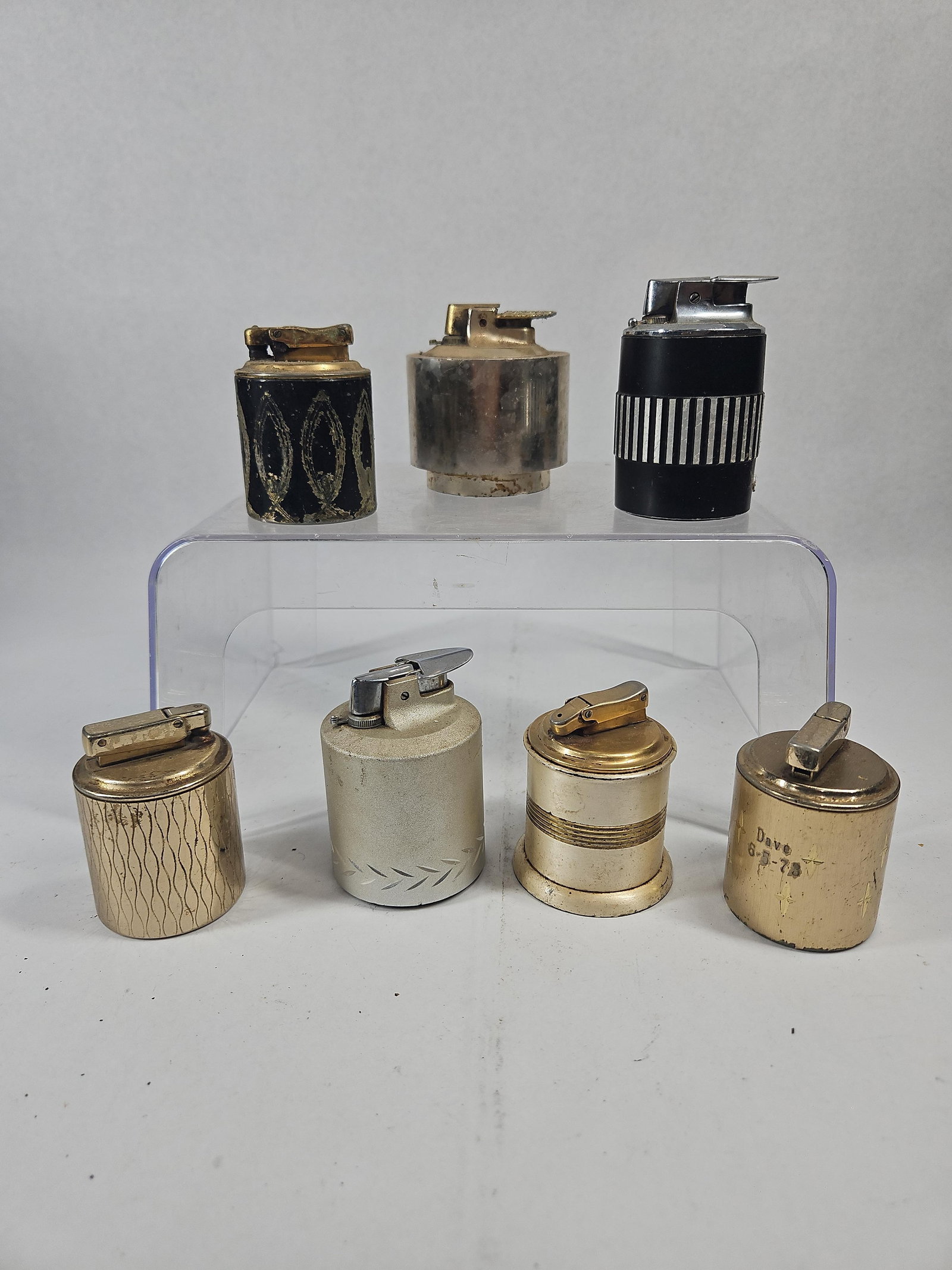 Ronson, Colibri & Kreisler Table: An assortment of mid-century modern table lighters in various cylindrical and tapered forms. The group features multiple finishes including gold-tone, silver-tone, and black enamel. A silver-tone