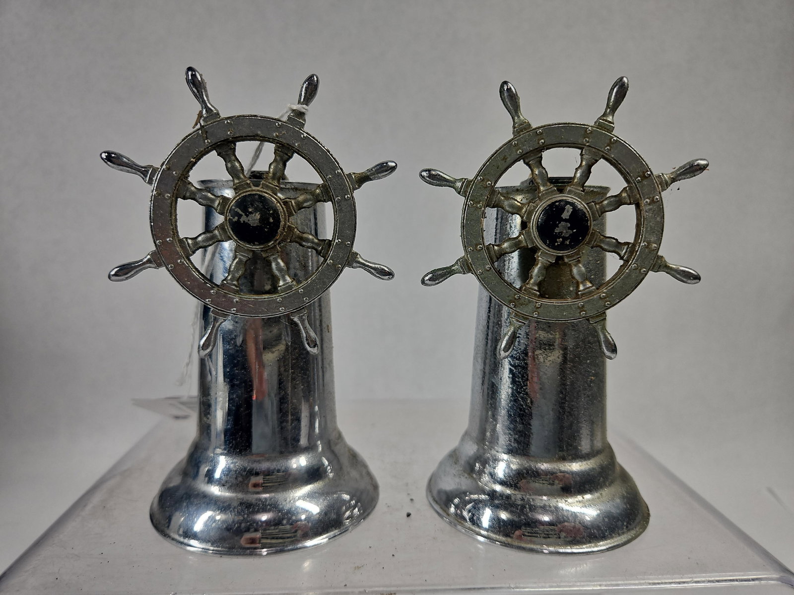 Pair Chrome Ship Wheel Table Lighters: A pair of vintage nautical-themed table lighters, each designed as a miniature ship's wheel or helm. The lighters are constructed from cast base metal with a polished chrome finish. Each piece