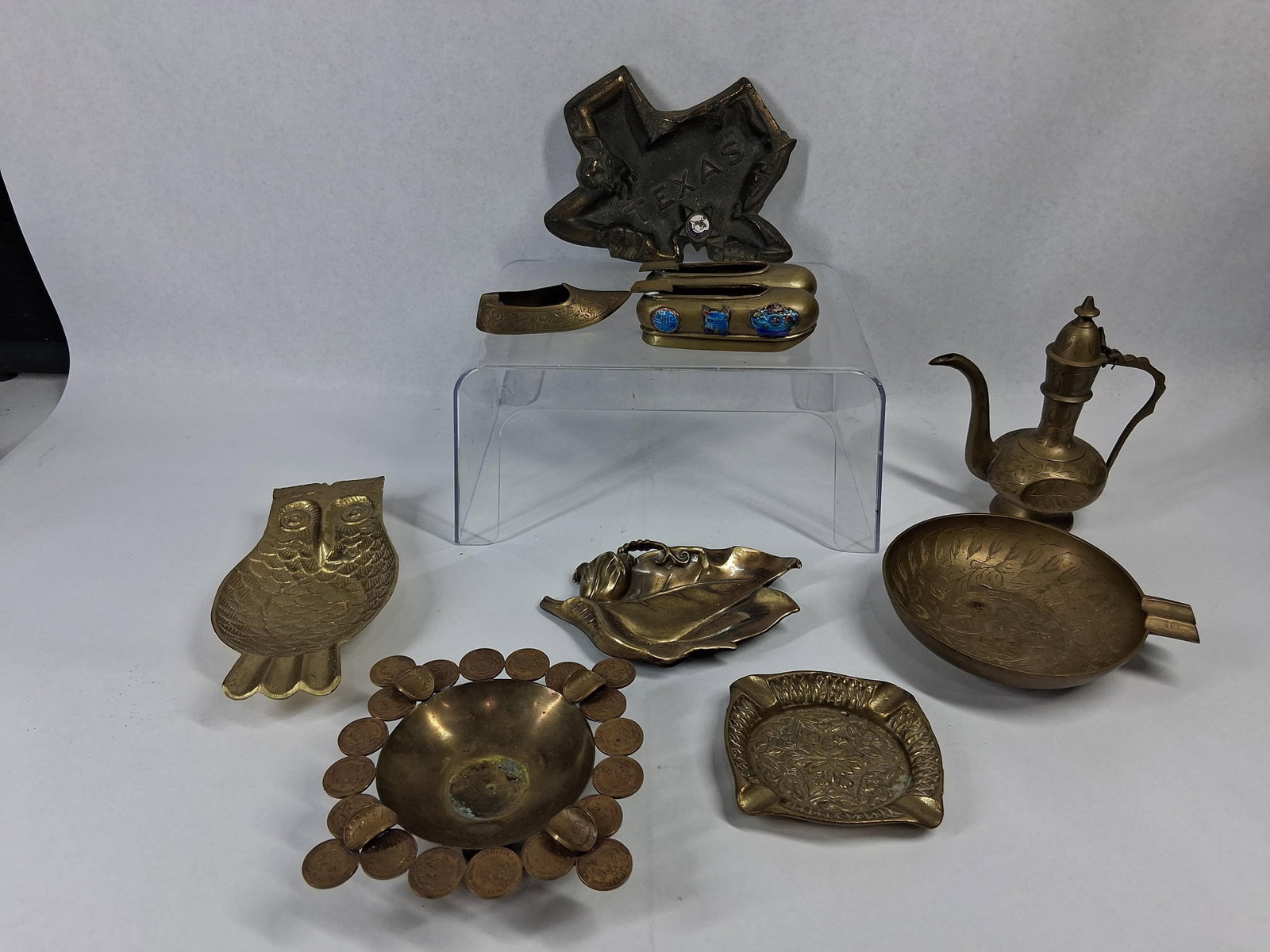 Vtg Brass Metalware & Souvenir Ashtrays: A collection of decorative brass metalware items including several novelty and souvenir ashtrays alongside a small lidded vessel. The group includes a cast brass ashtray shaped like the state of
