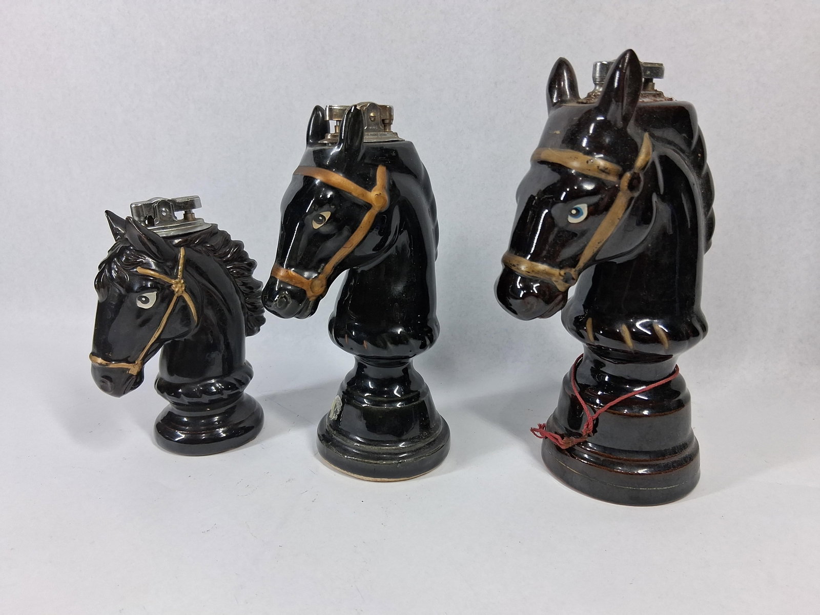 Japanese Ceramic Horse-Head Lighters: A set of three graduated vintage Japanese glazed ceramic table lighters designed as stylized horse-head chess knights. Each piece is finished in a high-gloss dark brown glaze with hand-painted