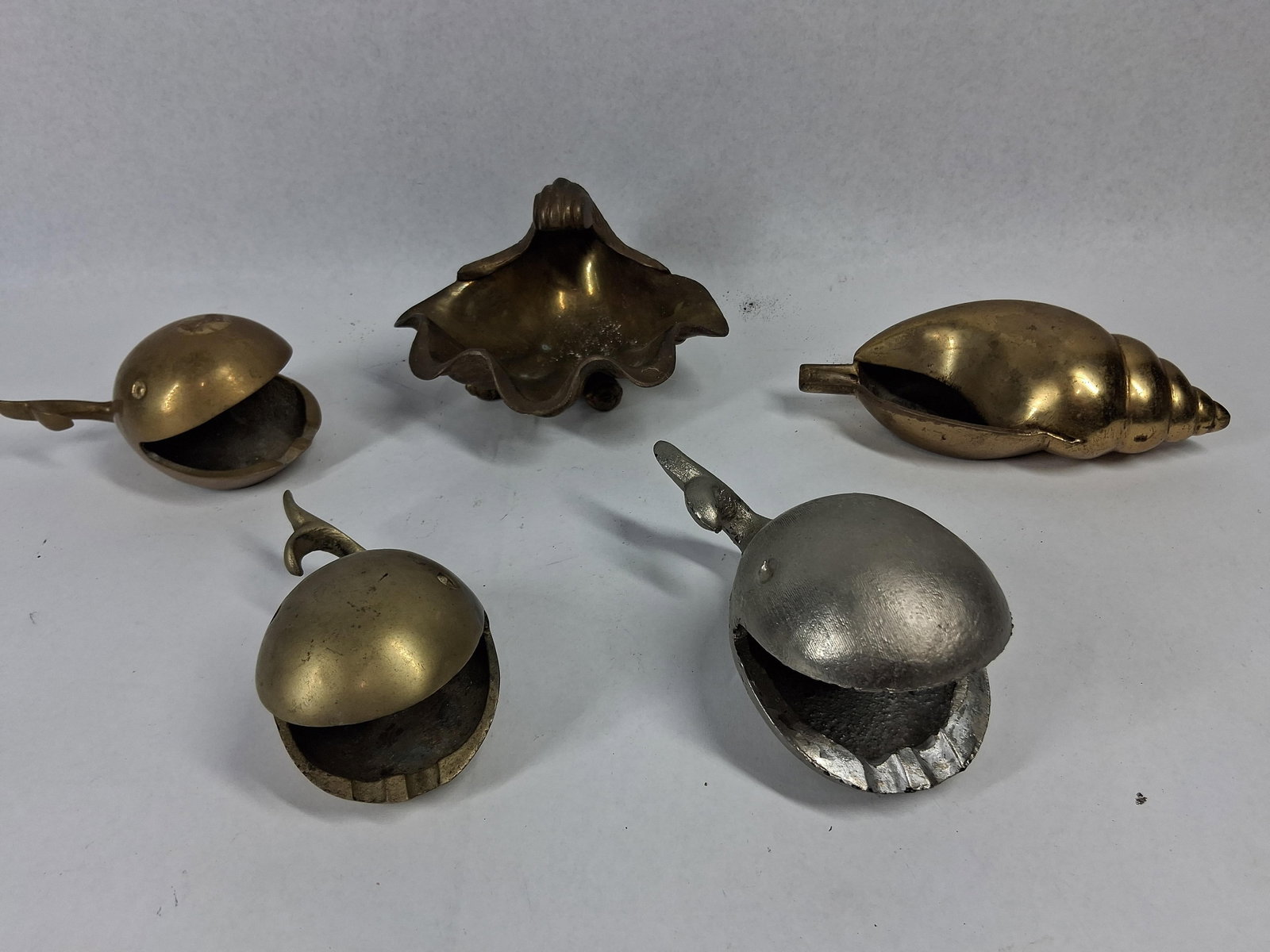 5 Marine Cast Metal Ashtrays & Dishes: A collection of five cast metal items featuring marine motifs, consisting of four pieces in solid brass and one in a silver-toned metal. The set includes three stylized whales with wide-open mouths,