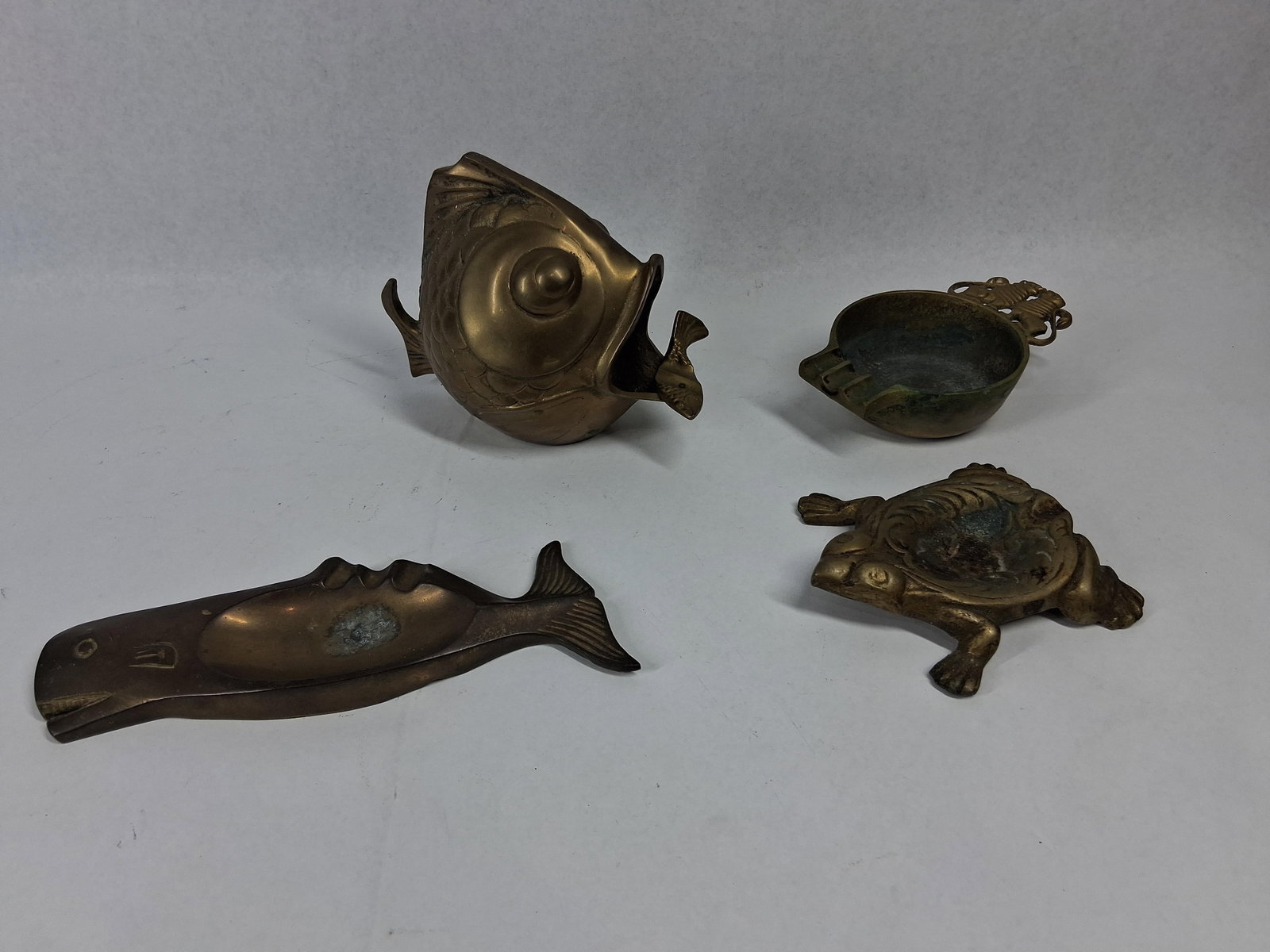 Israeli Nordia Brass Animal Accessories: This collection of cast brass accessories features various animal-themed pieces designed for decorative and smoking use. The group consists of an Israeli ashtray, a large fish vessel, a whale