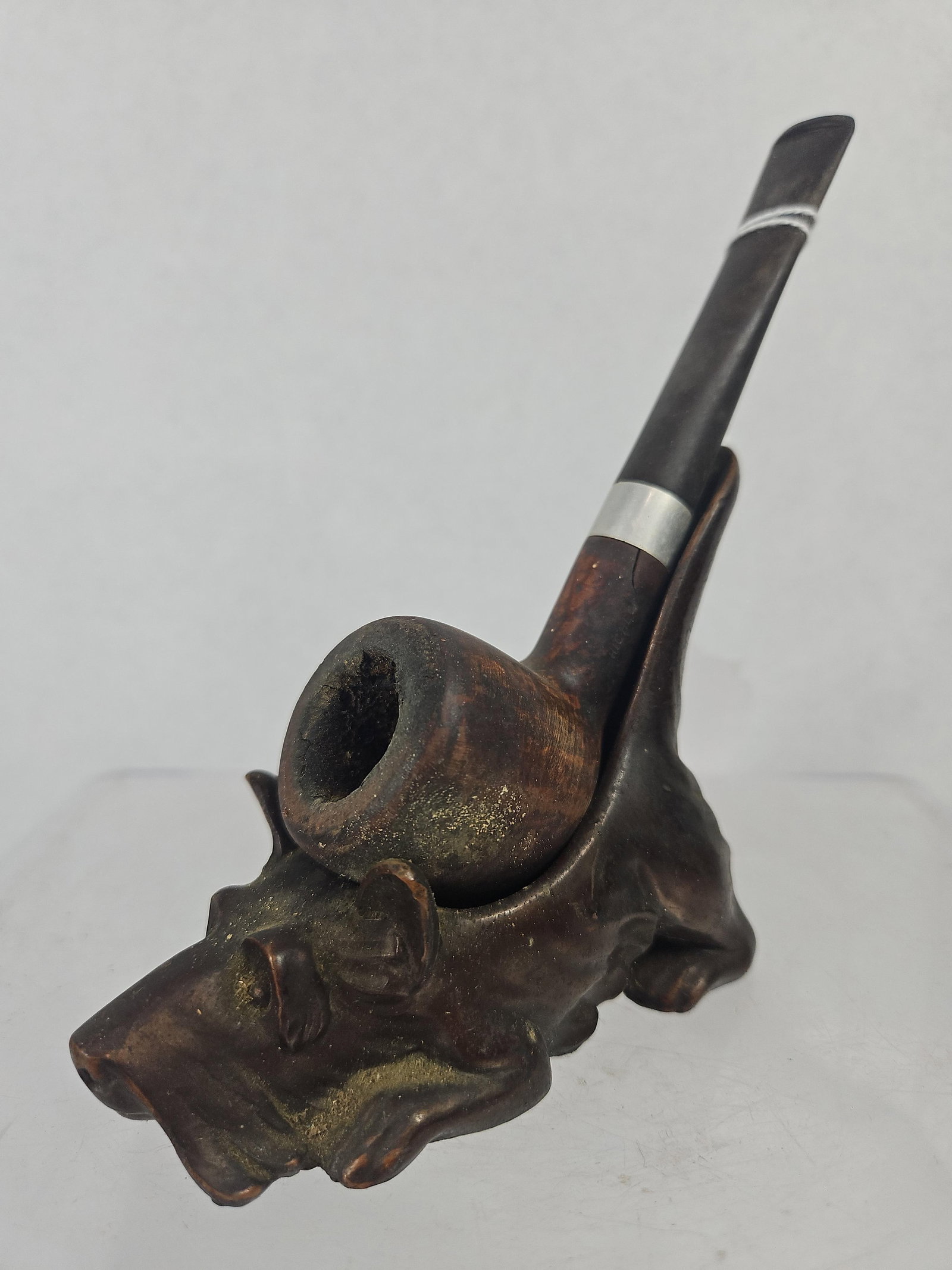 1935 Ronson Scottie Pipe Stand & Pipe: A vintage smoking pipe and accompanying figural metal pipe stand produced by Art Metal Works, Inc. The stand is constructed from a dark, bronze-finished white metal and depicts a recumbent Scottish