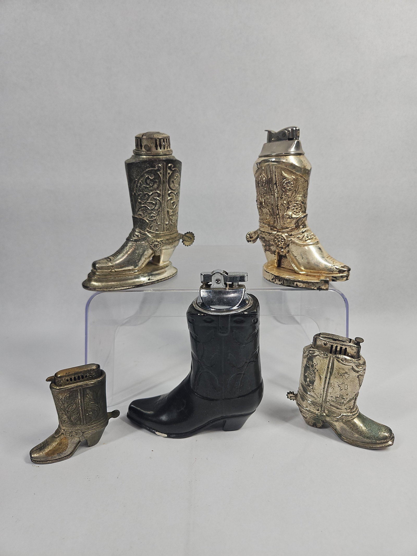Vtg Japanese Cowboy Boot Table Lighters: A collection of novelty table lighters designed in the form of western cowboy boots. The assortment includes four silver-plated cast metal boots and one molded black ceramic boot. The metal examples