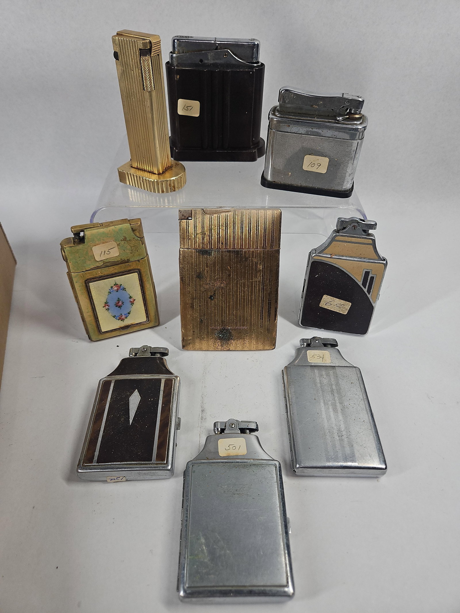 Ronson & Elgin American Lighters/Cases: This assortment includes several cigarette case and lighter combination units and standalone desk lighters. One combination case features a tan and black Art Deco geometric enamel motif on the
